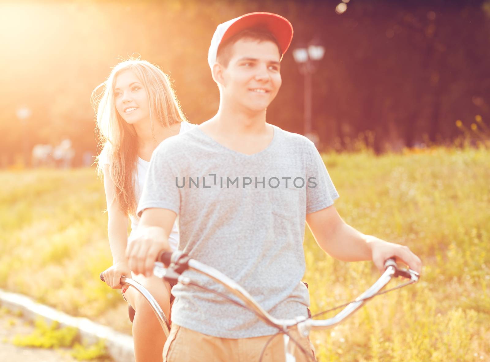 Happy couple riding a bicycle in the park outdoors by vlad_star