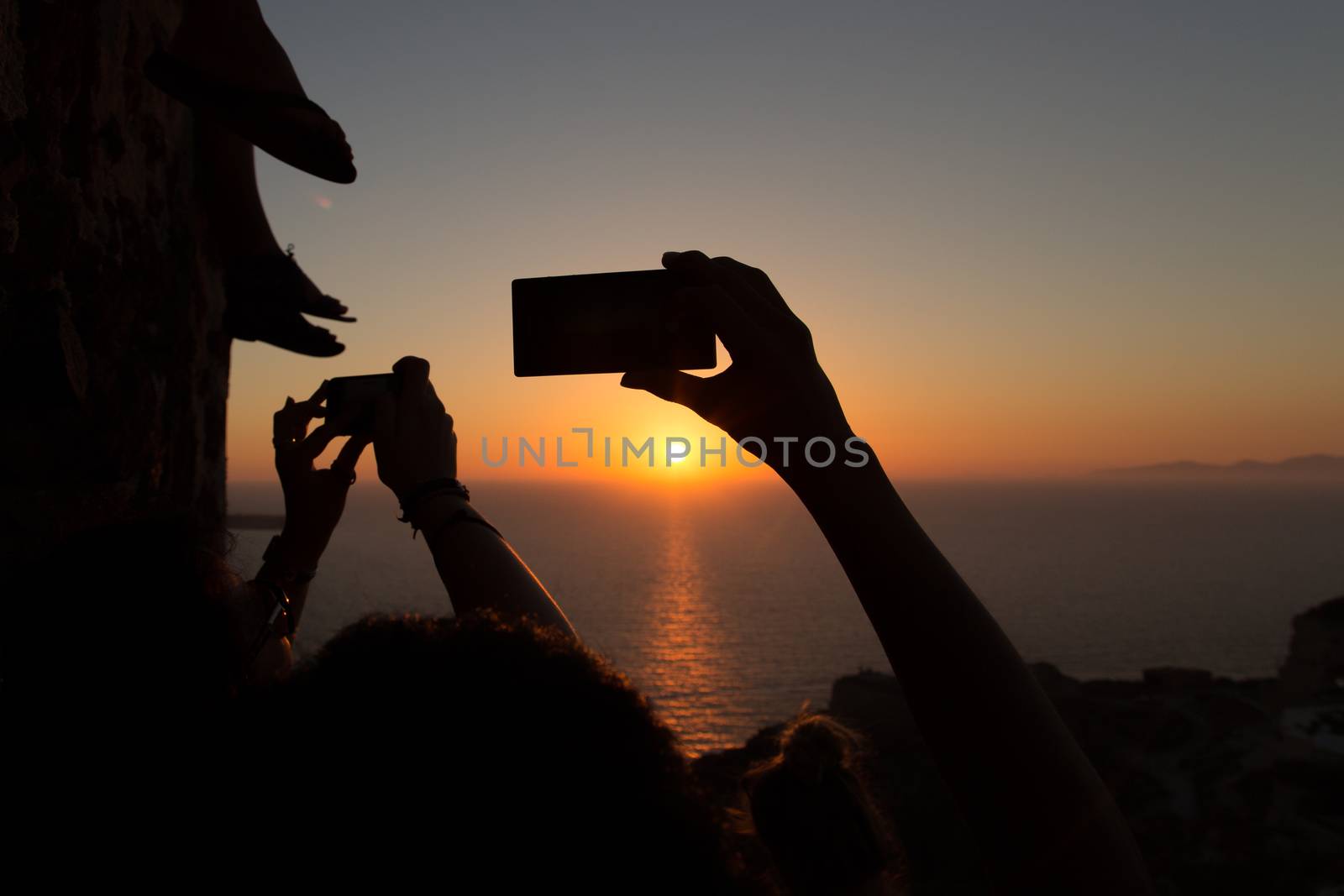 Silhouettes of people taking sunsets pictures with their smartphones