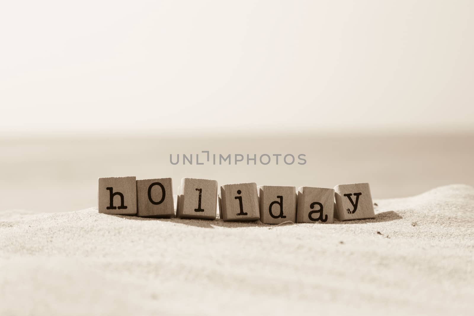 Holiday season word with sand beach background in sepia tone  by vinnstock