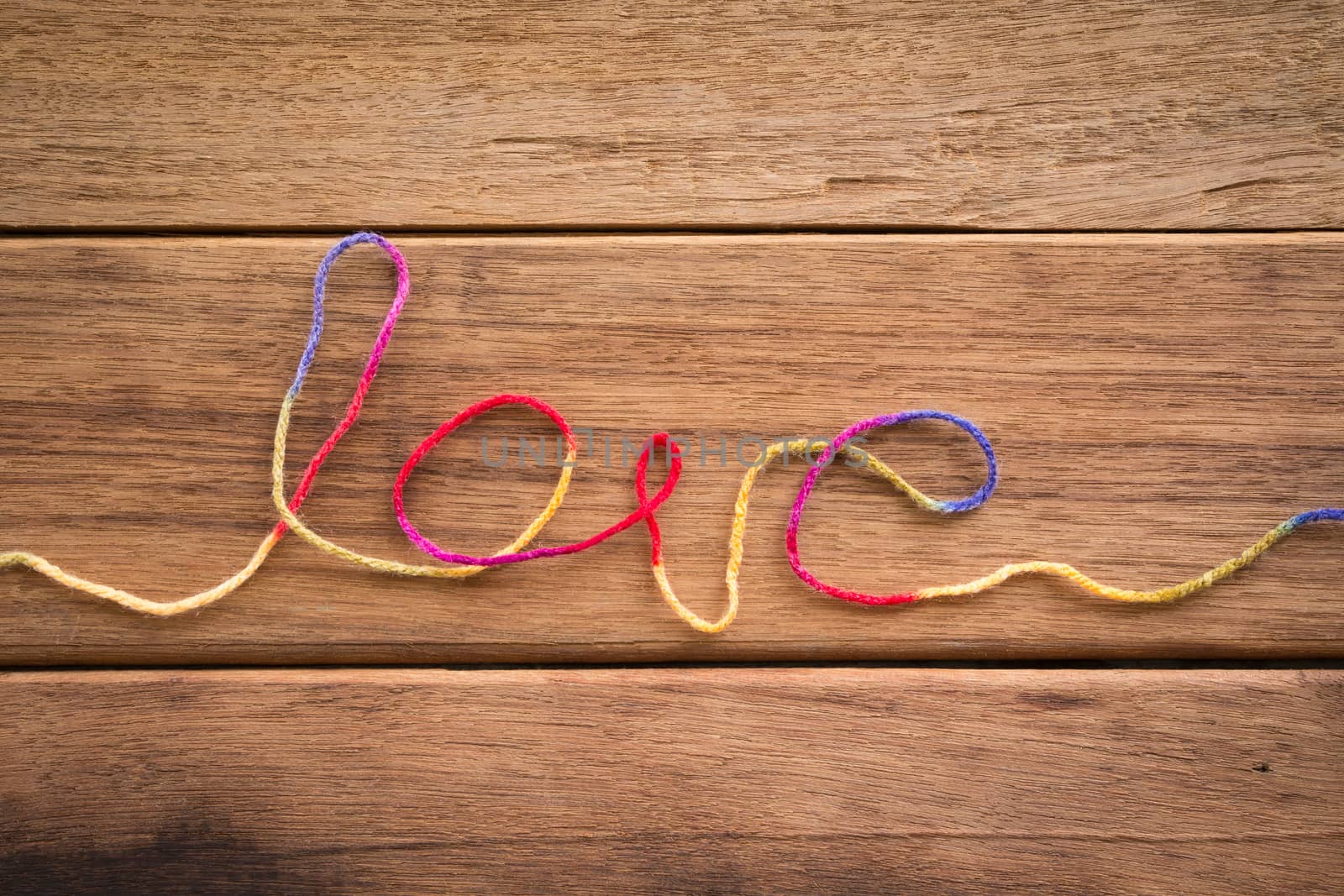 Sweet love word from colorful yarn place on wood texture, wedding and valentine's day symbol