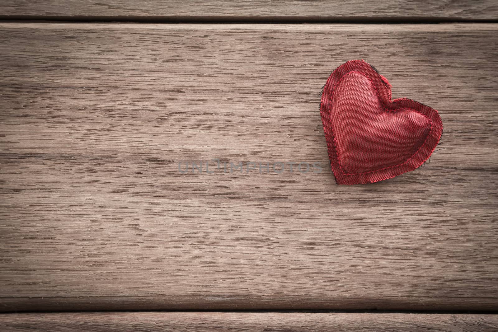 Red heart handmade craft from silk cloth place on right side of  wood background with space for text, retro style with vignette, valentine's day symbol