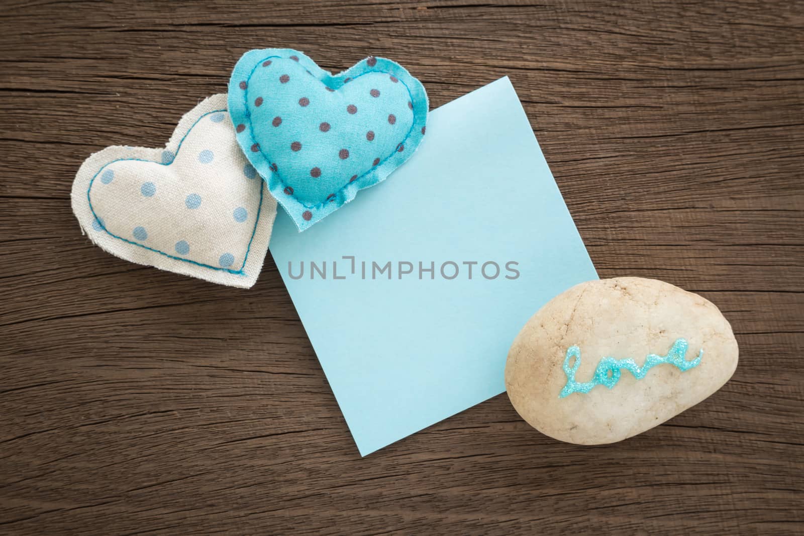 Blue hearts handmade crafts from polka dot cotton cloth with love word on pebble and blank paper note place on wood background with vignette,  anniversary and valentine's day symbol