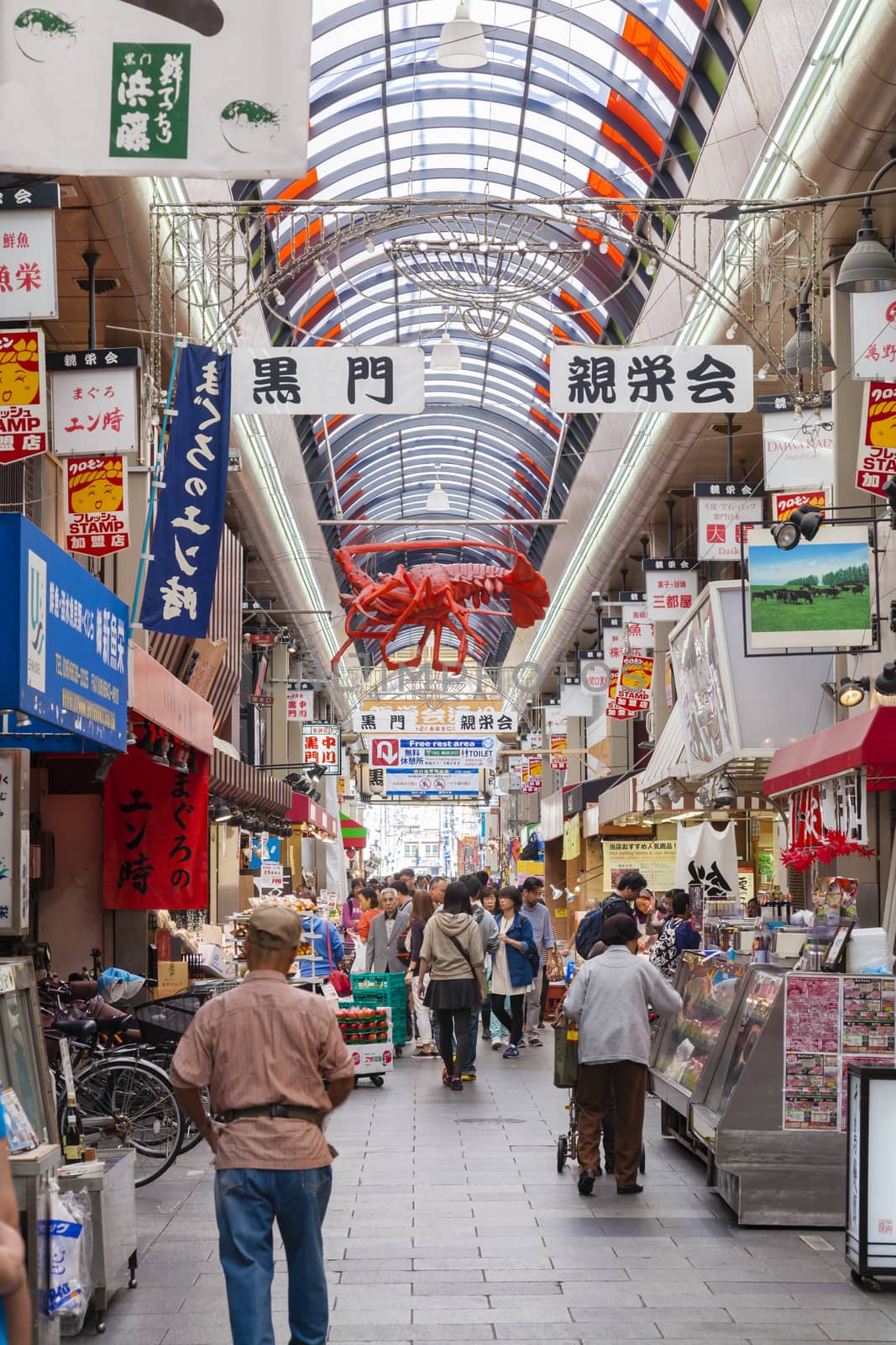 Osaka, Japan - Oct 26: People shopping in the Kuromon Market in Osaka, Japan on Oct 26, 2014.  The Kuromon Market has been called 'Osaka's Kitchen' since it opened as many cooks in Osaka come here to get the ingredients.