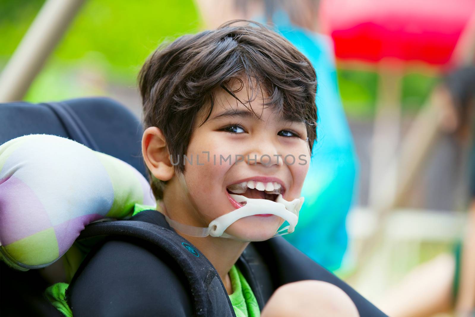 Handsome disabled eight year old biracial boy smiling and relaxing in wheelchair