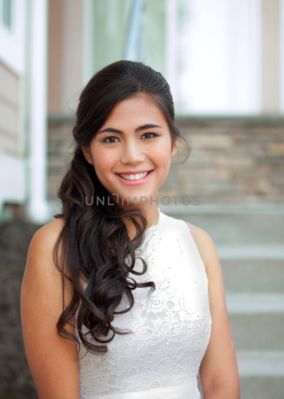 Beautiful biracial bride in white lace wedding dress, smiling outdoors