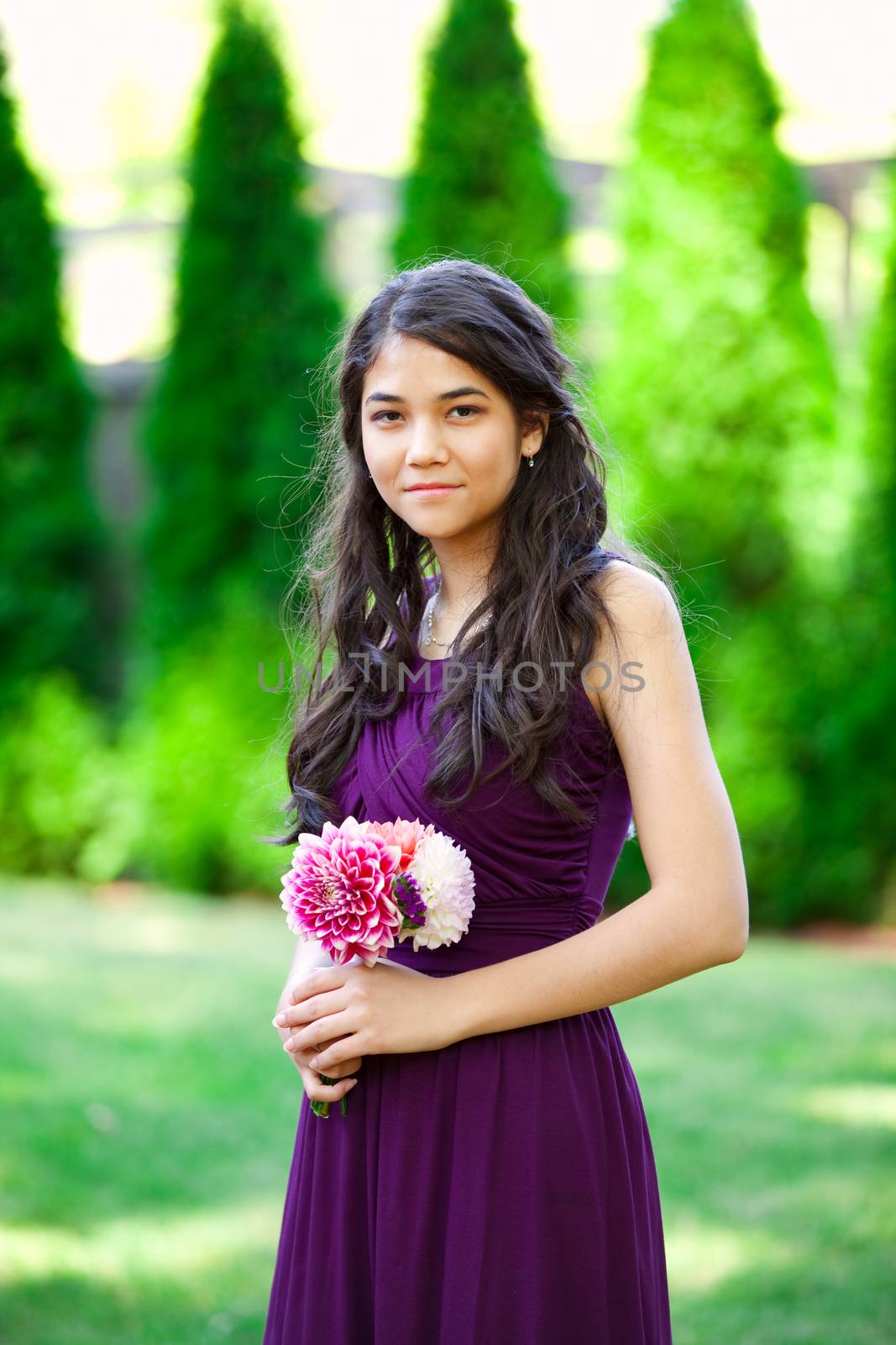 Beautiful biracial bridesmaid in purple dress, smiling outdoors