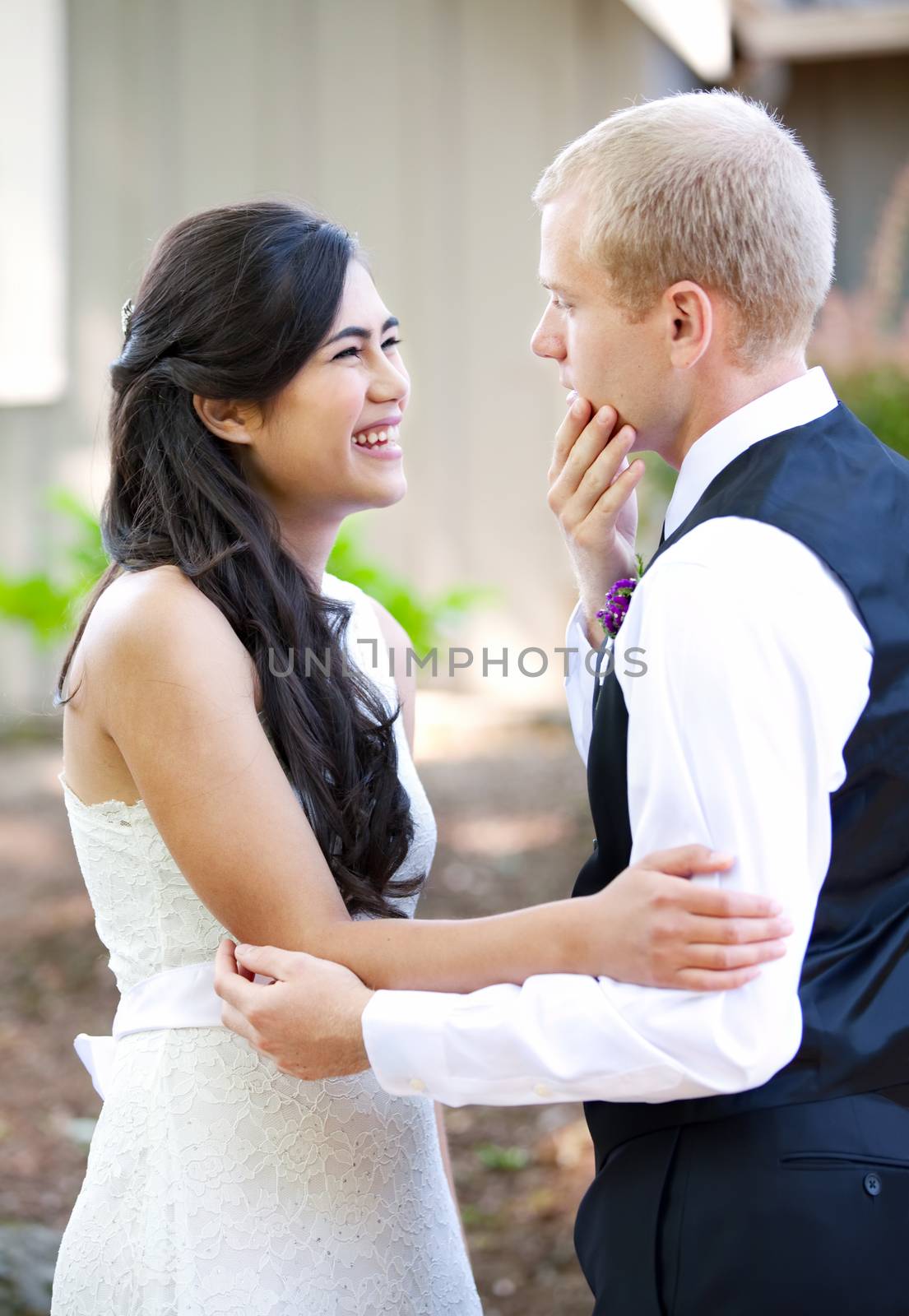 Handsome Caucasian groom talking with his biracial bride outdoor by jarenwicklund