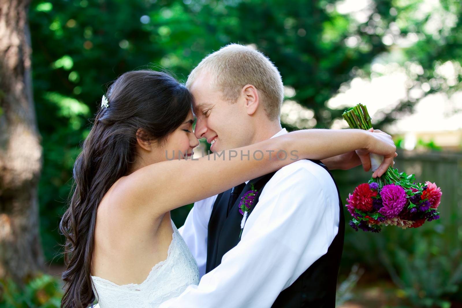 Caucasian groom holding his biracial bride, smiling. Diverse cou by jarenwicklund