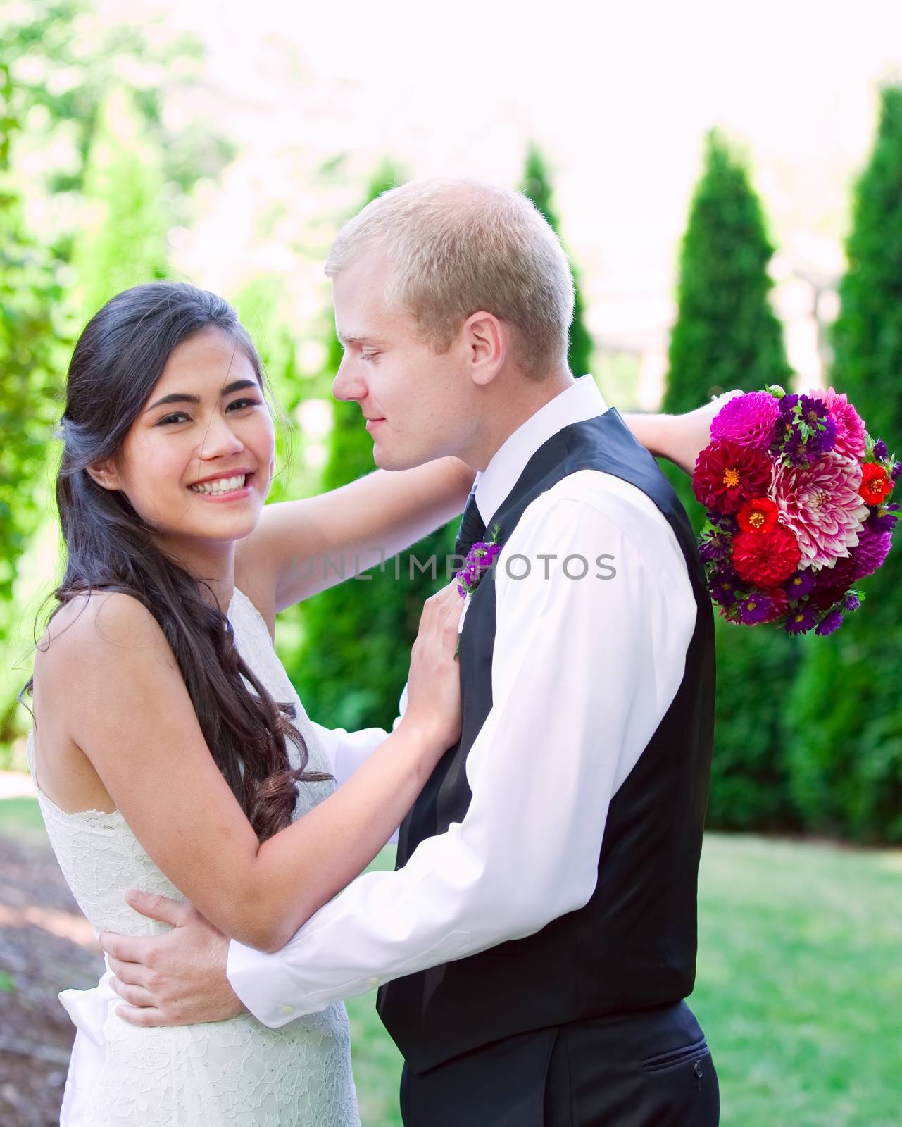 Caucasian groom holding his biracial bride, smiling. Diverse cou by jarenwicklund