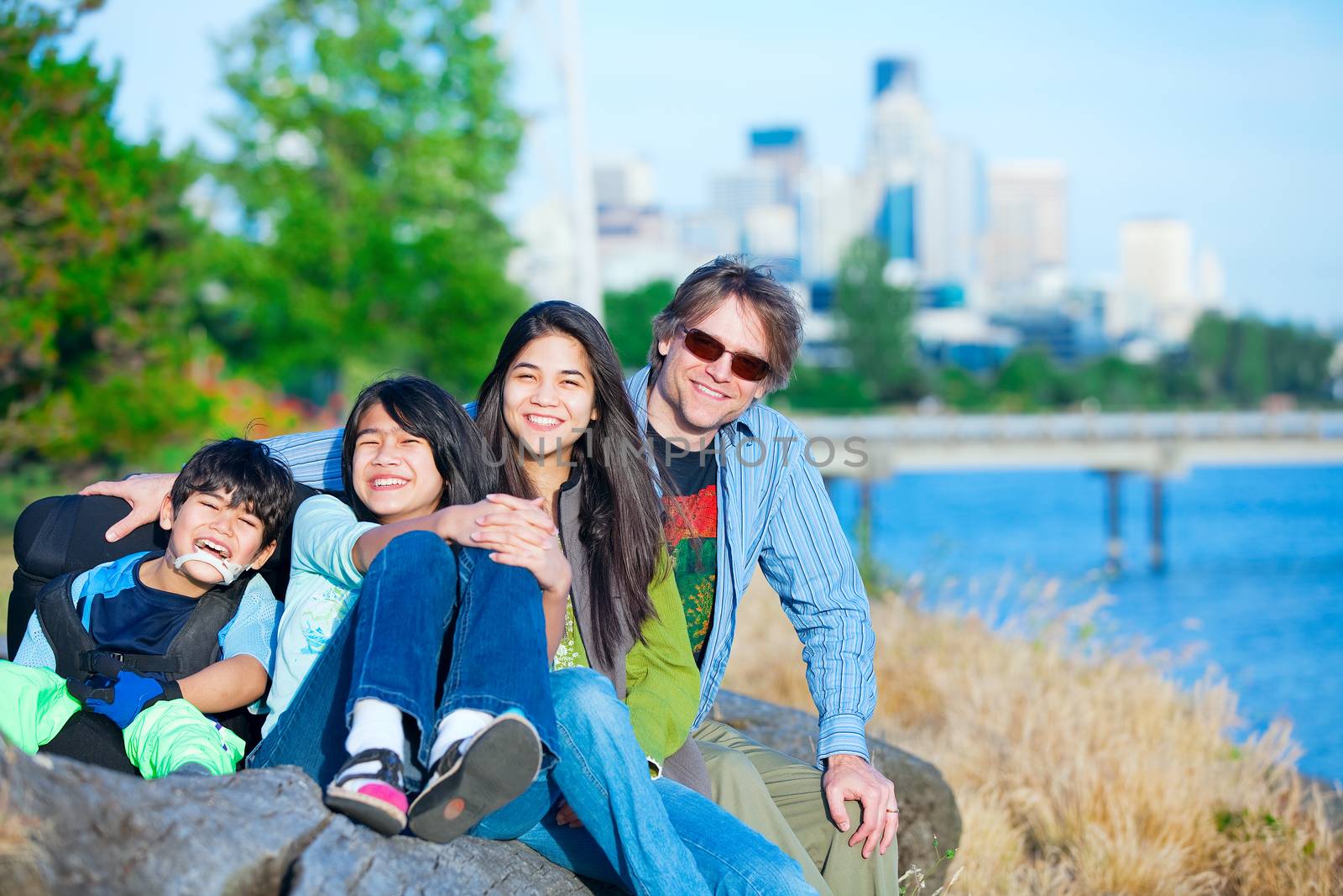 Disabled boy in wheelchair with family outdoors on sunny day, wi by jarenwicklund