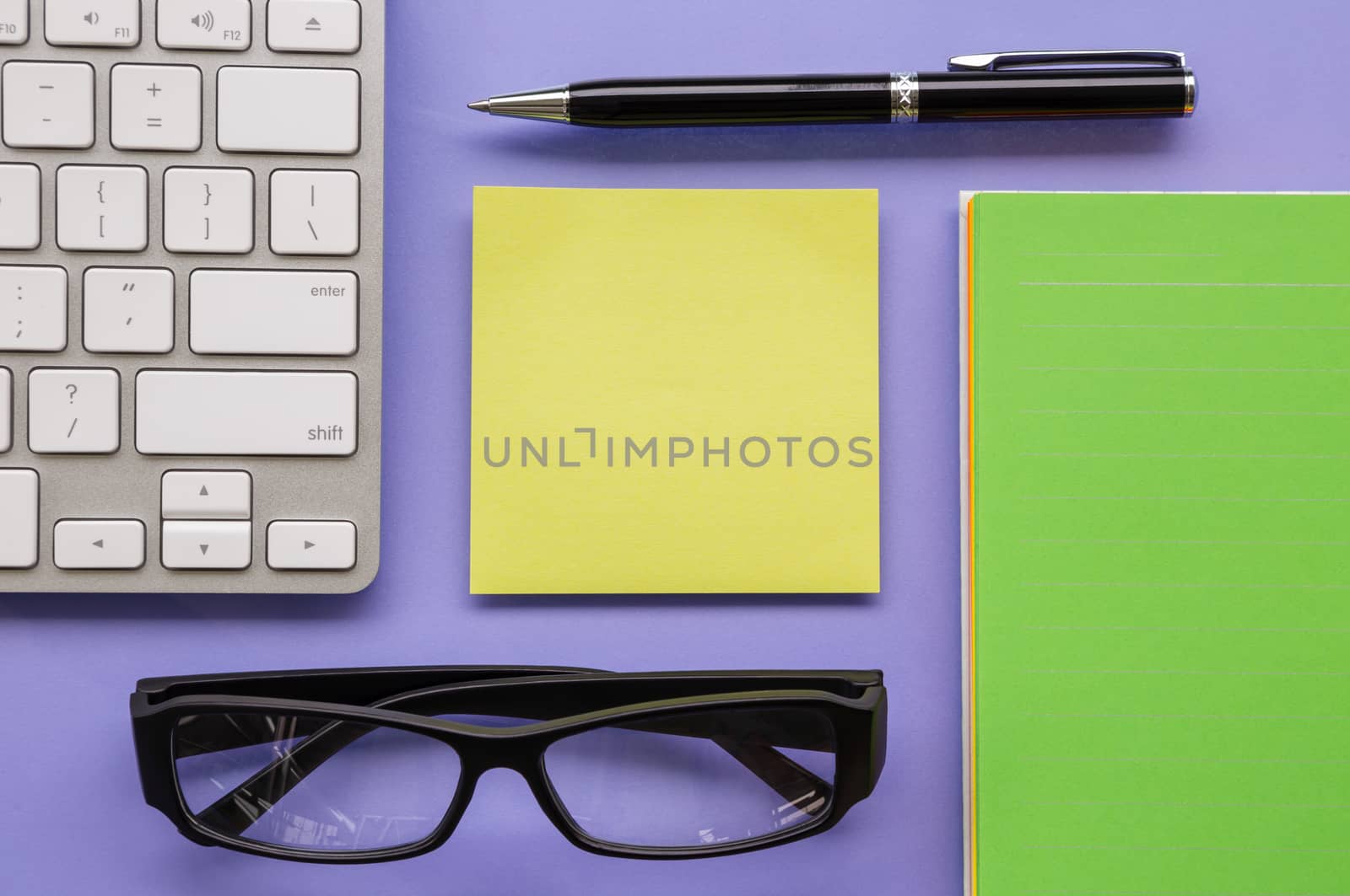 Blank yellow notepad putting on office table  with pen, keyboard, book and glasses sort orderly
