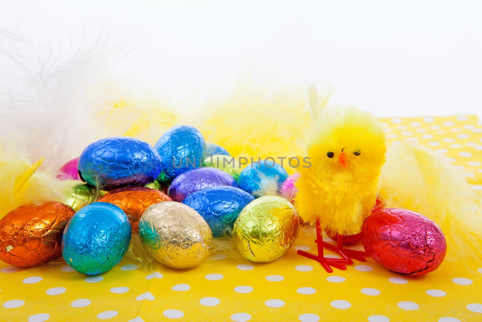 Easter scene with chicken and colorful chocolate eggs on yellow napkin