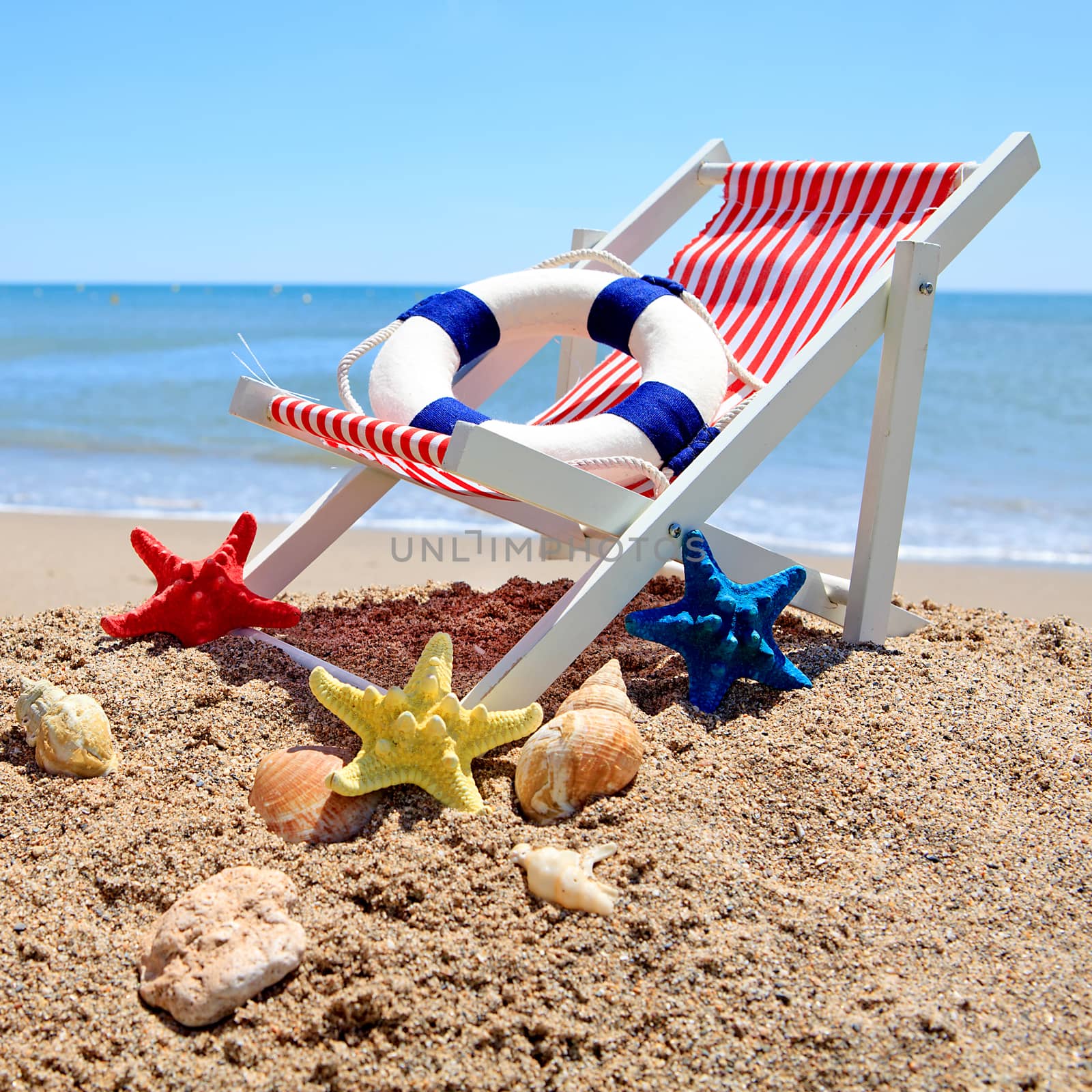 Beach chair near the ocean with shells on sunny day