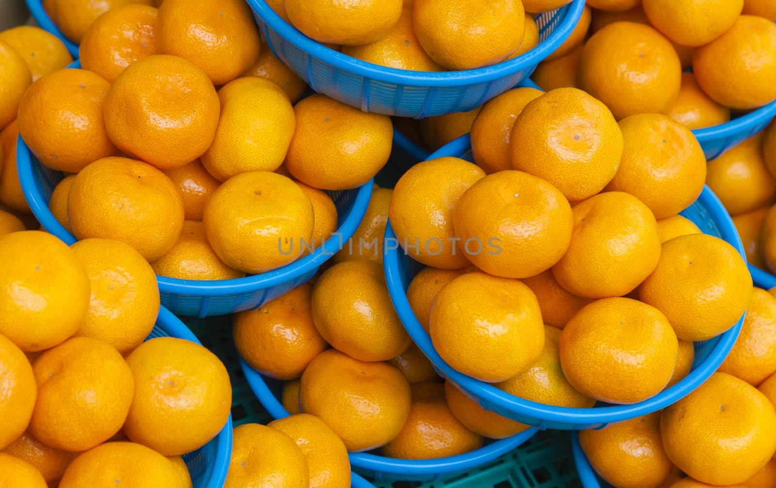 Oranges in baskets for sale in a food market by ymgerman