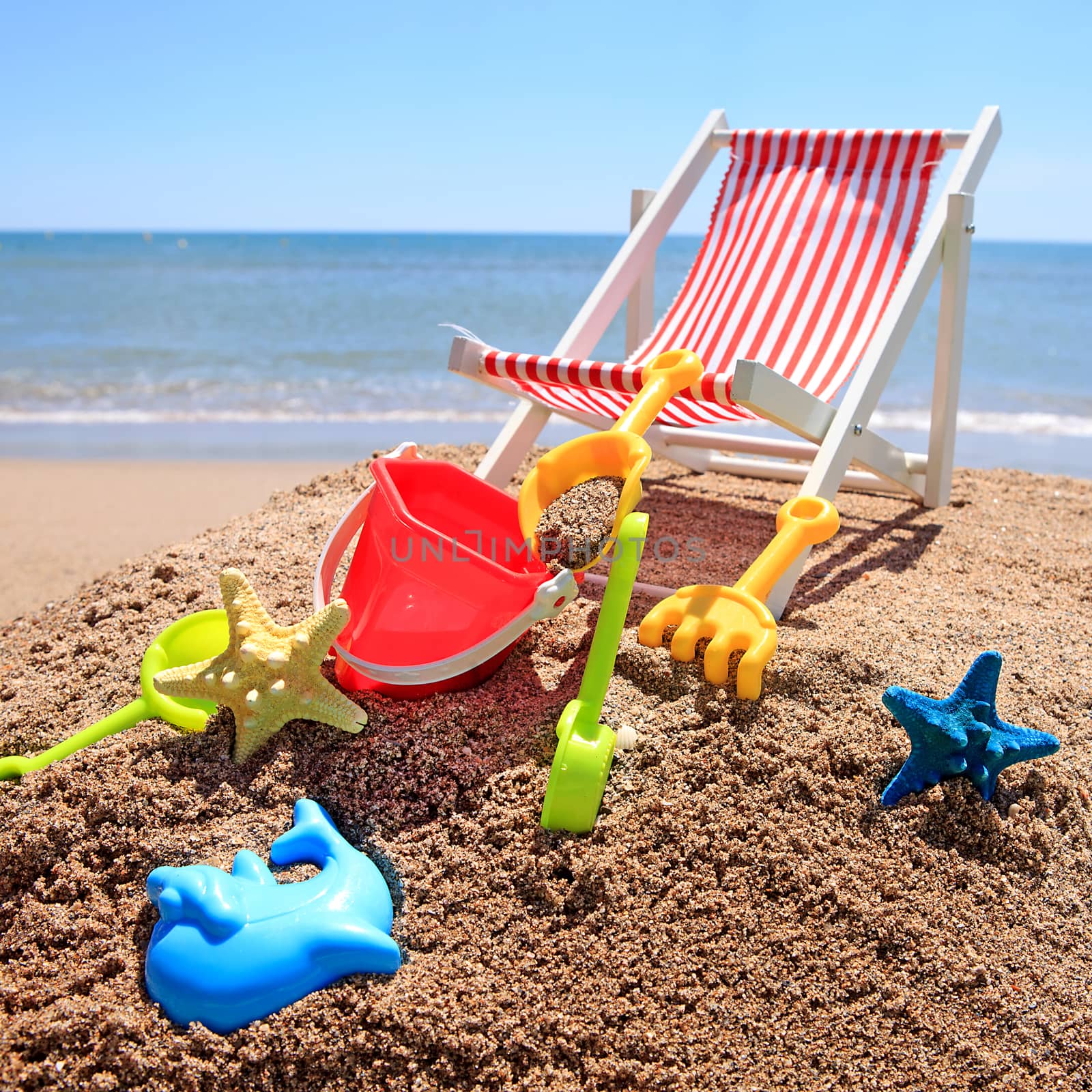 Beach chair near the ocean with plastic toys on sunny day