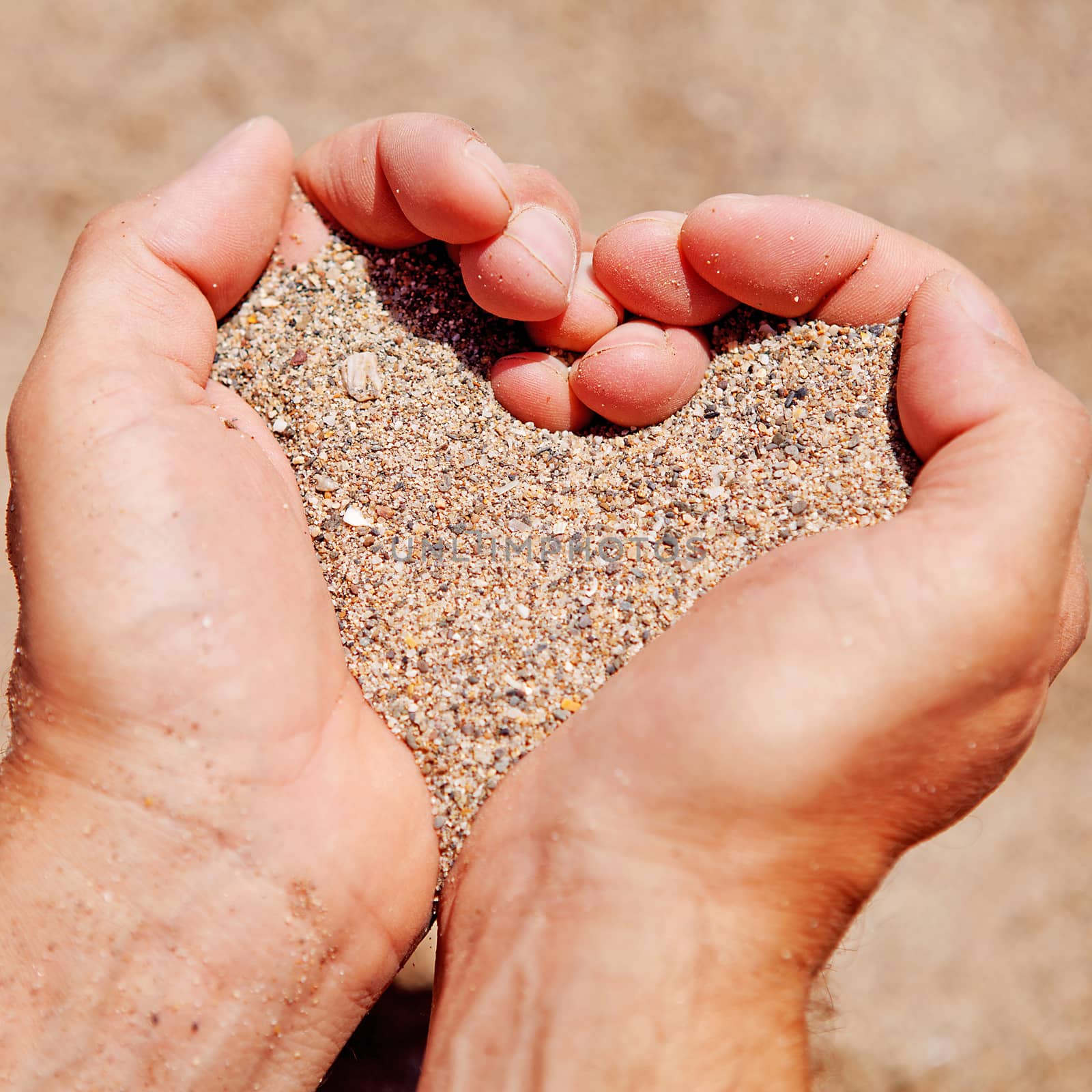 Hands in shape of hearts filled with sand