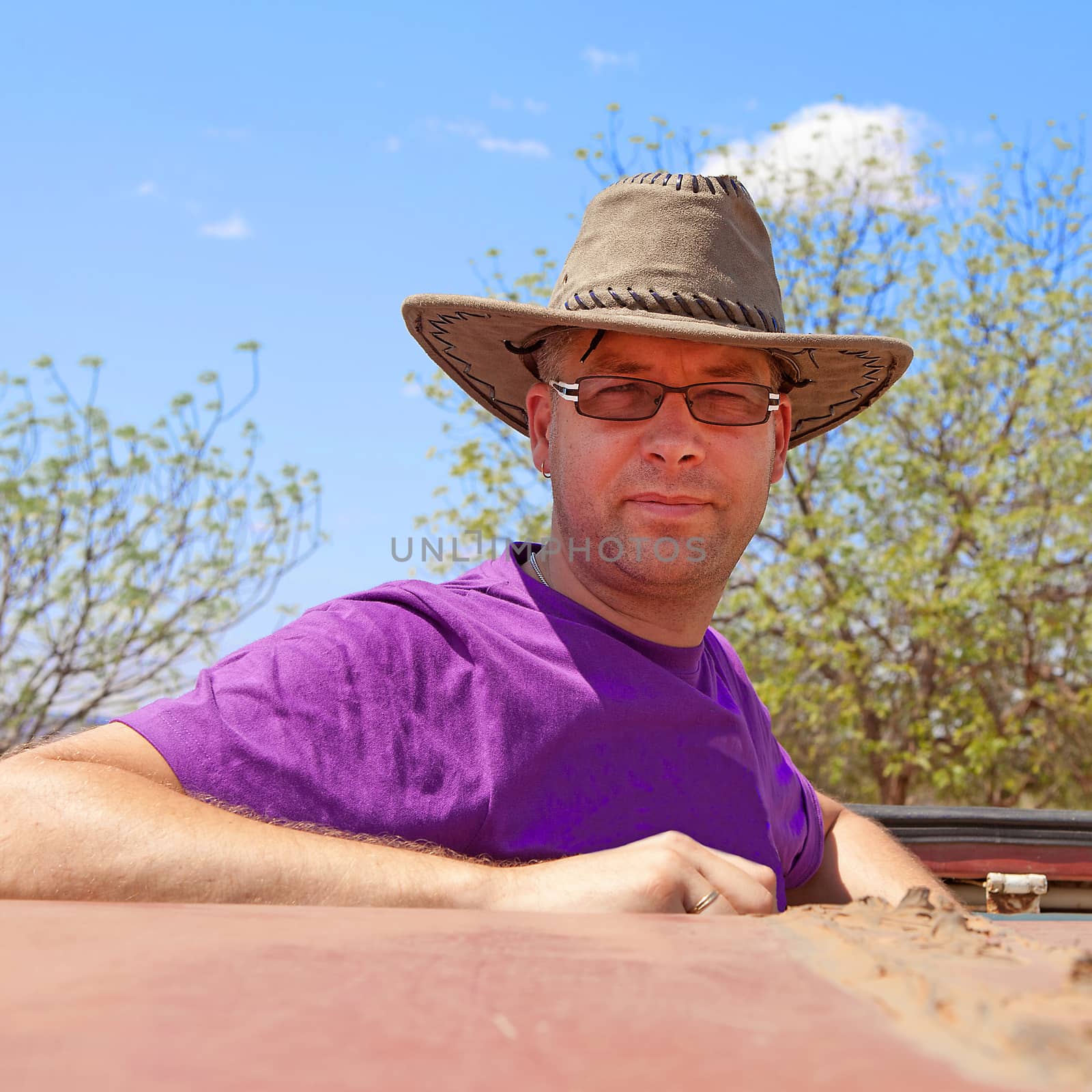 Going on safari: man standing on top of jeep with hat on