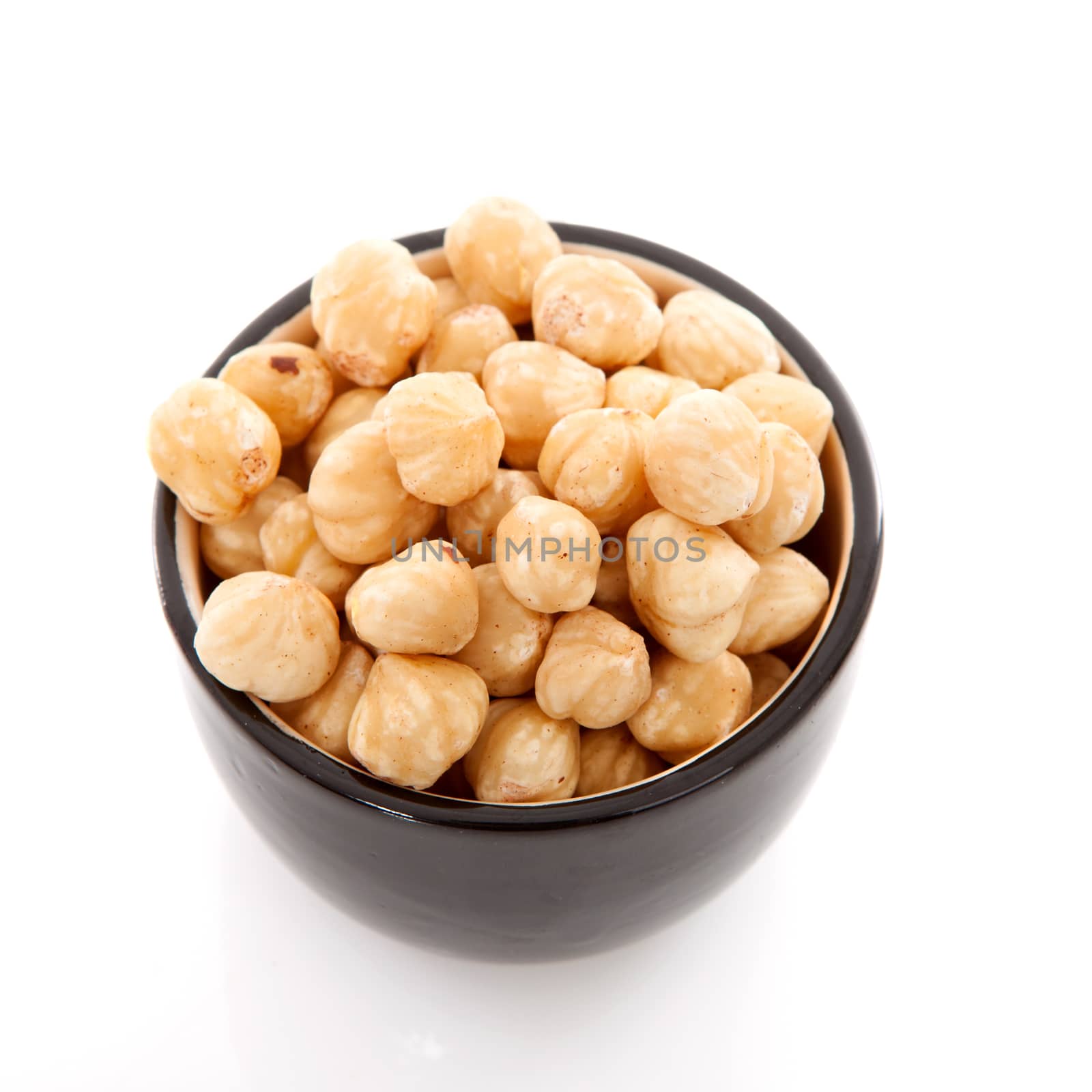 Bowl with hazelnuts over white background