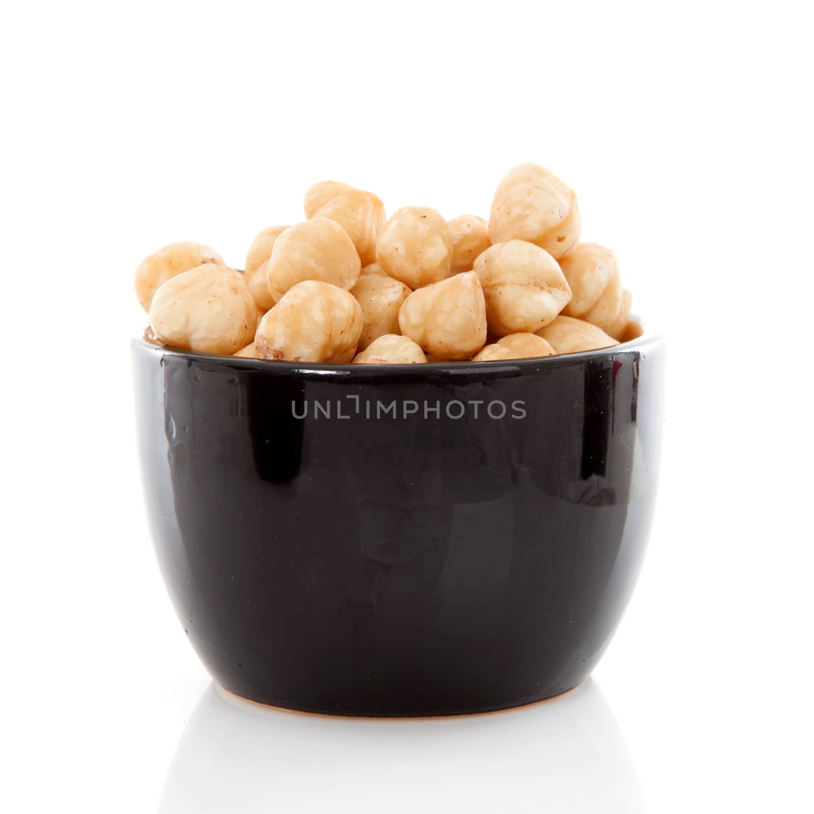 Bowl with hazelnuts over white background