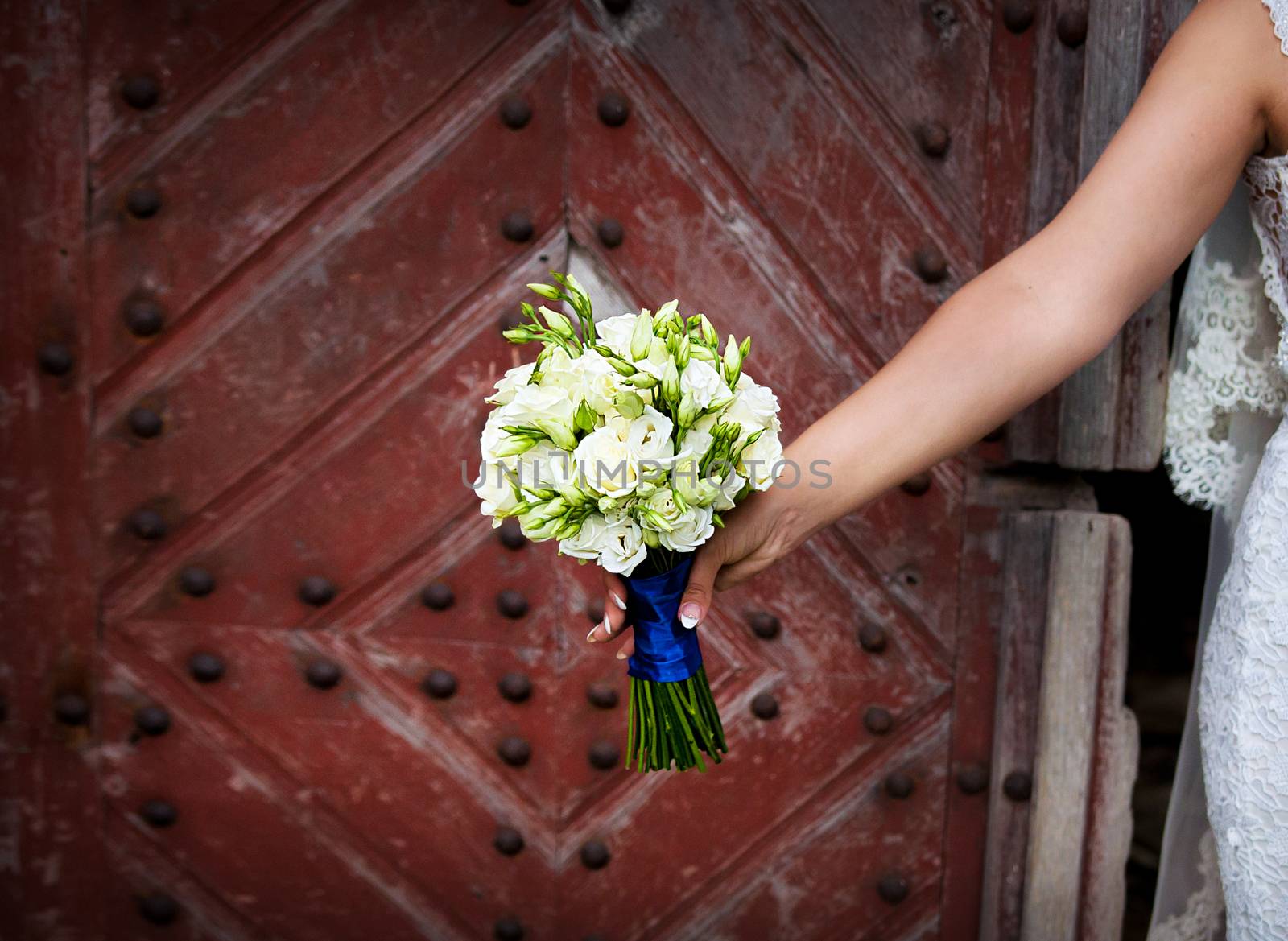 Bride holding beautiful wedding flowers bouquet on old wooden background