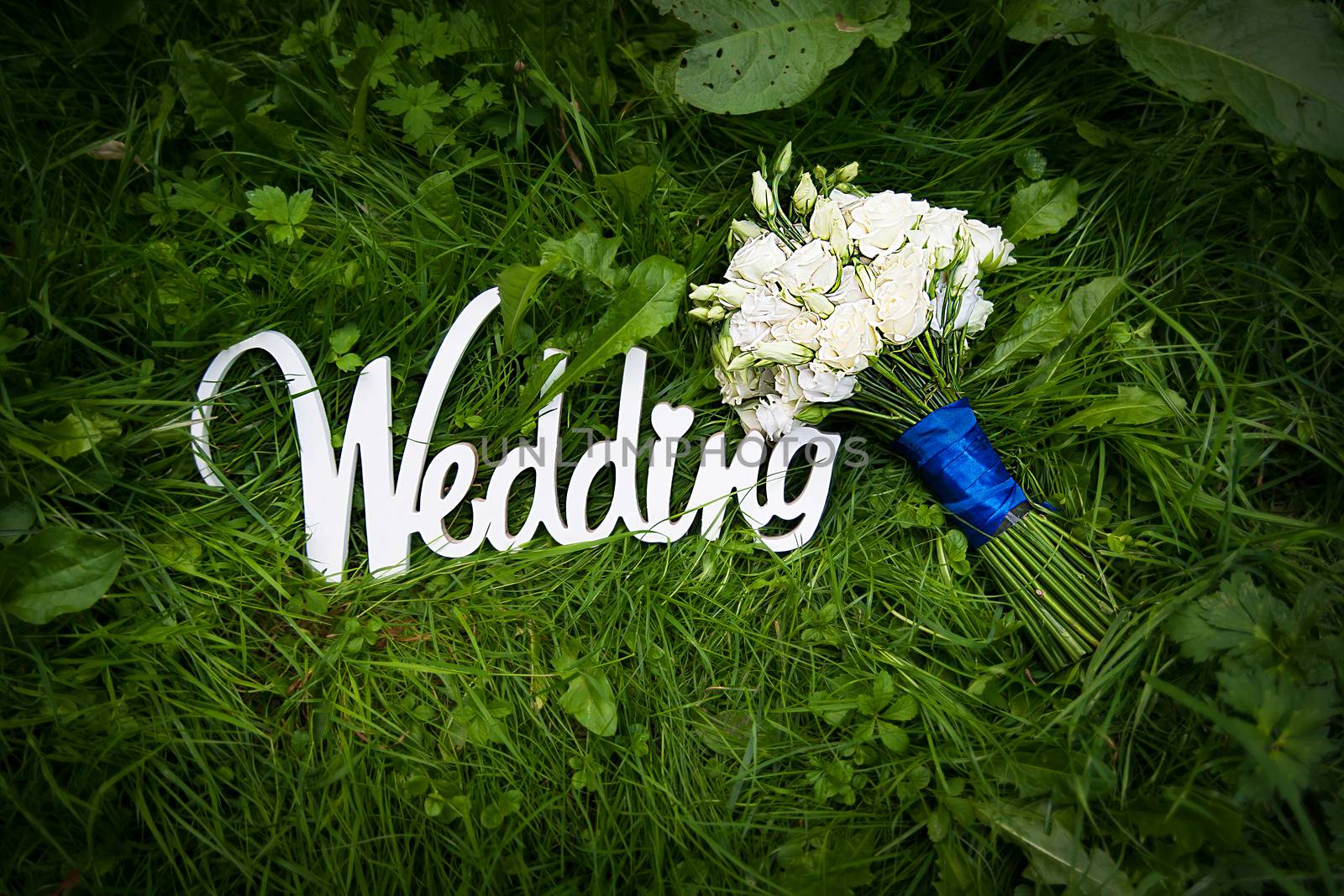 wedding letters with white flowers on grass.