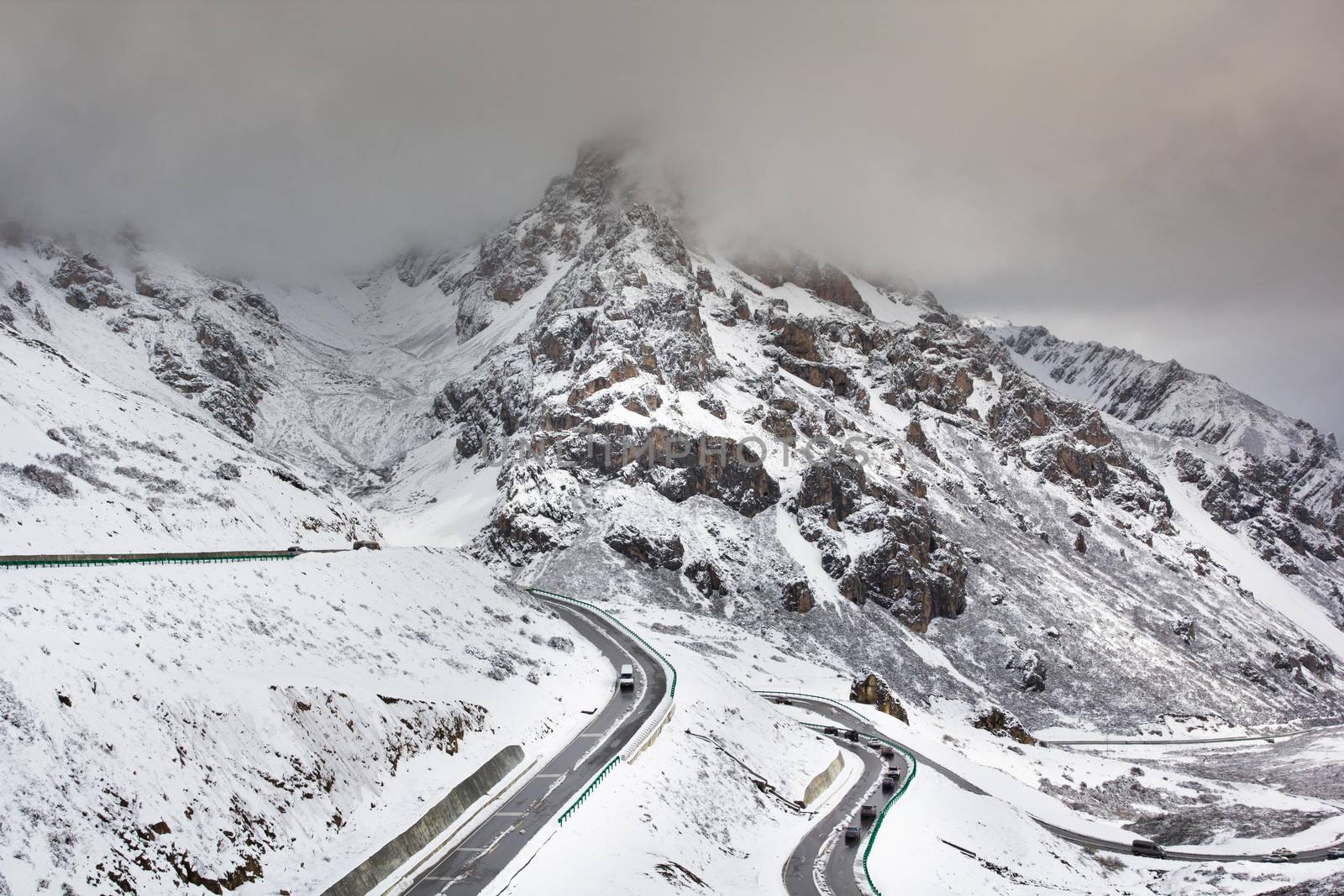 Road for traveling cross high mountain with snow and fog