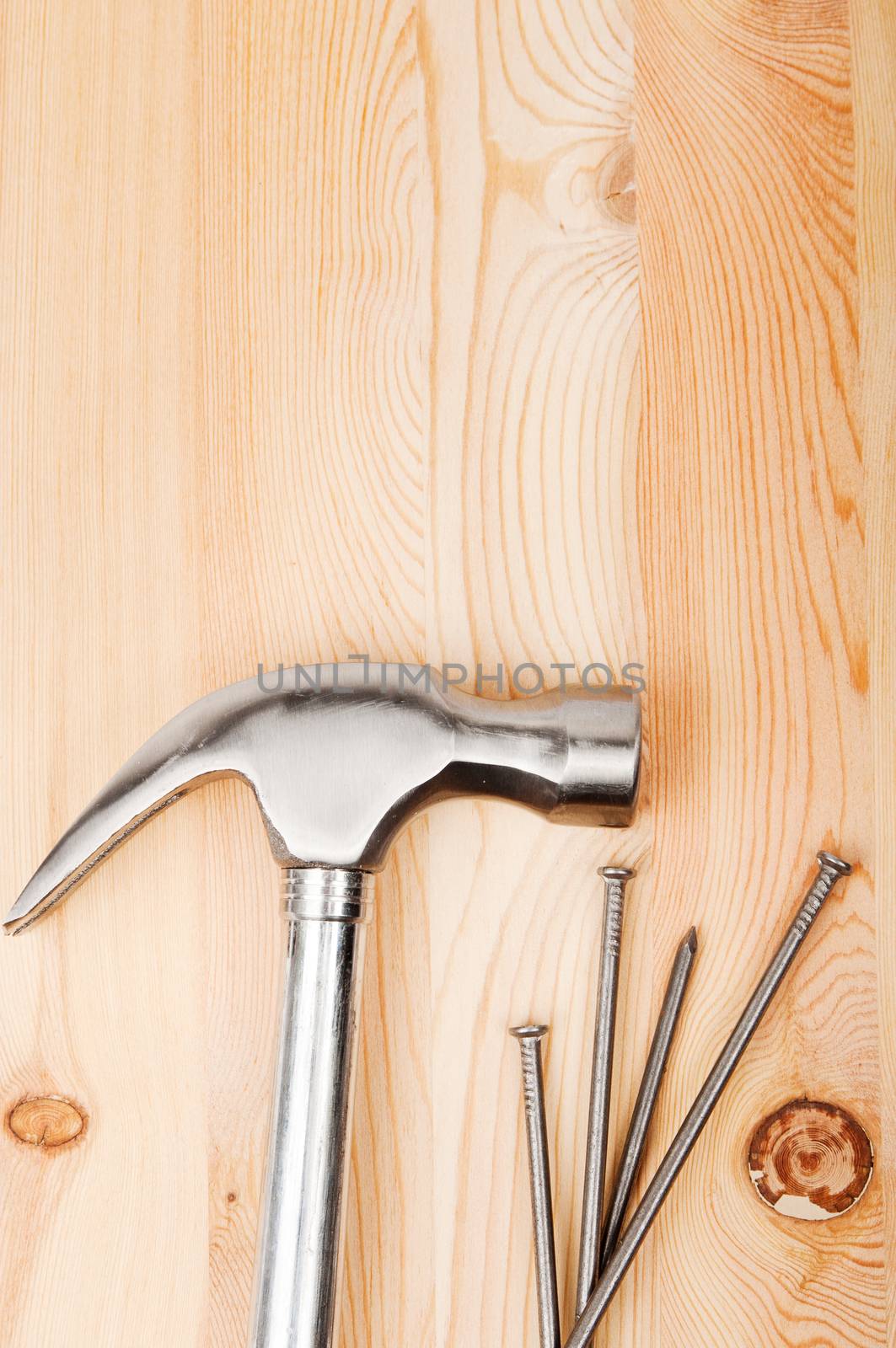 An image of Hammer with nails on wooden timber