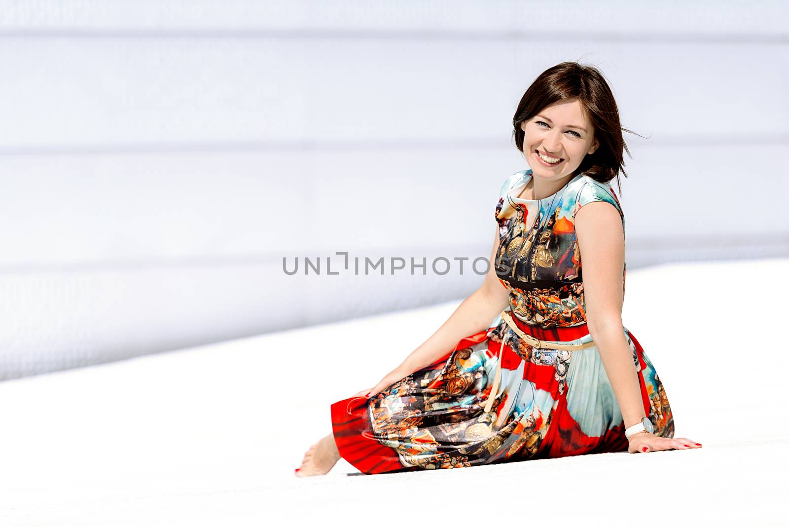 Model in dress posing on exterior set sitting angled by Nanisimova