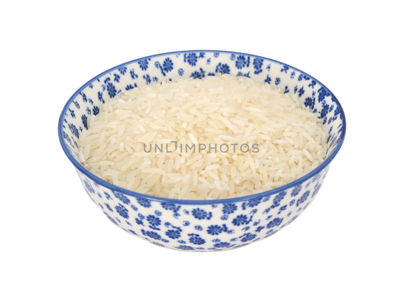 White long grain rice in a blue and white porcelain bowl with a floral design, isolated on a white background