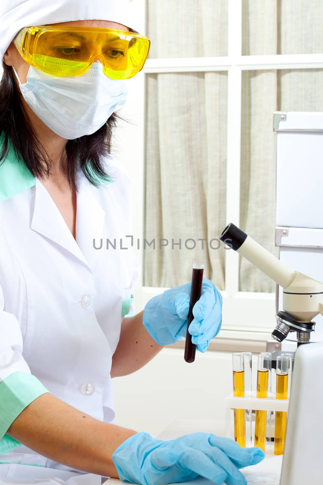 a female medical or scientific researcher or woman doctor looking at a test tube of dark solution in a laboratory