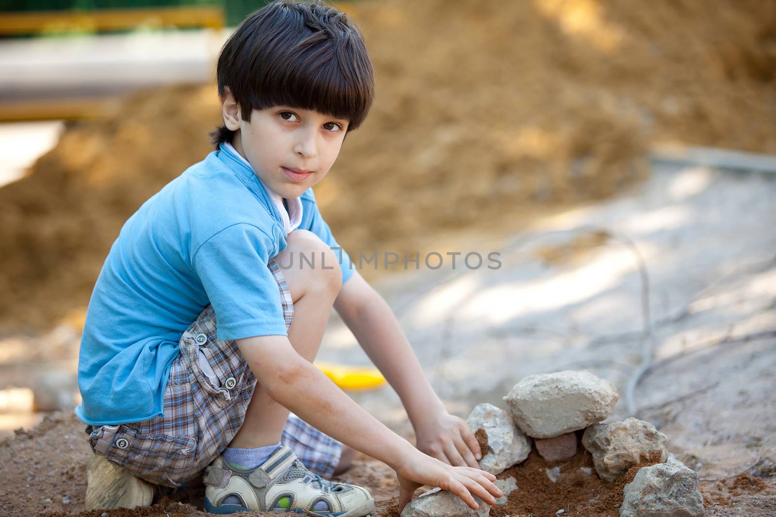 boy builds a house out of stones and sand