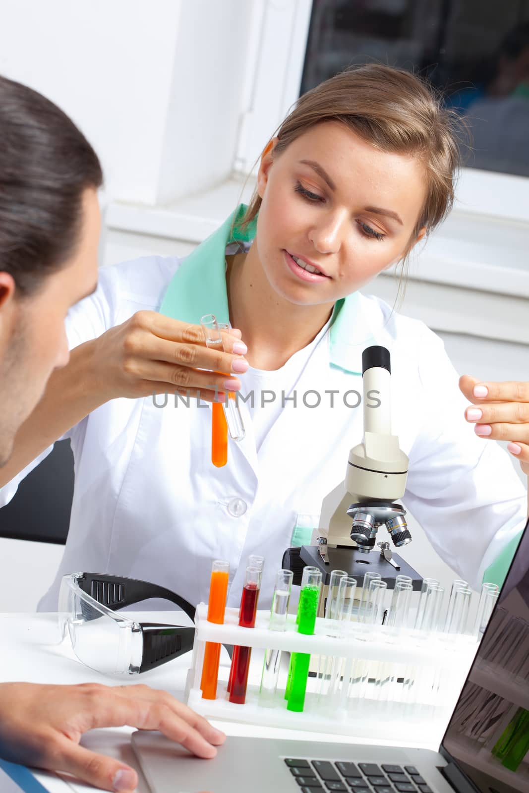 female scientist looking at liquid in test tube by Astroid