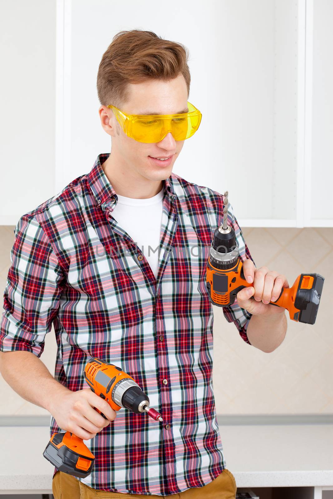 young worker chooses between a drill and screwdriver