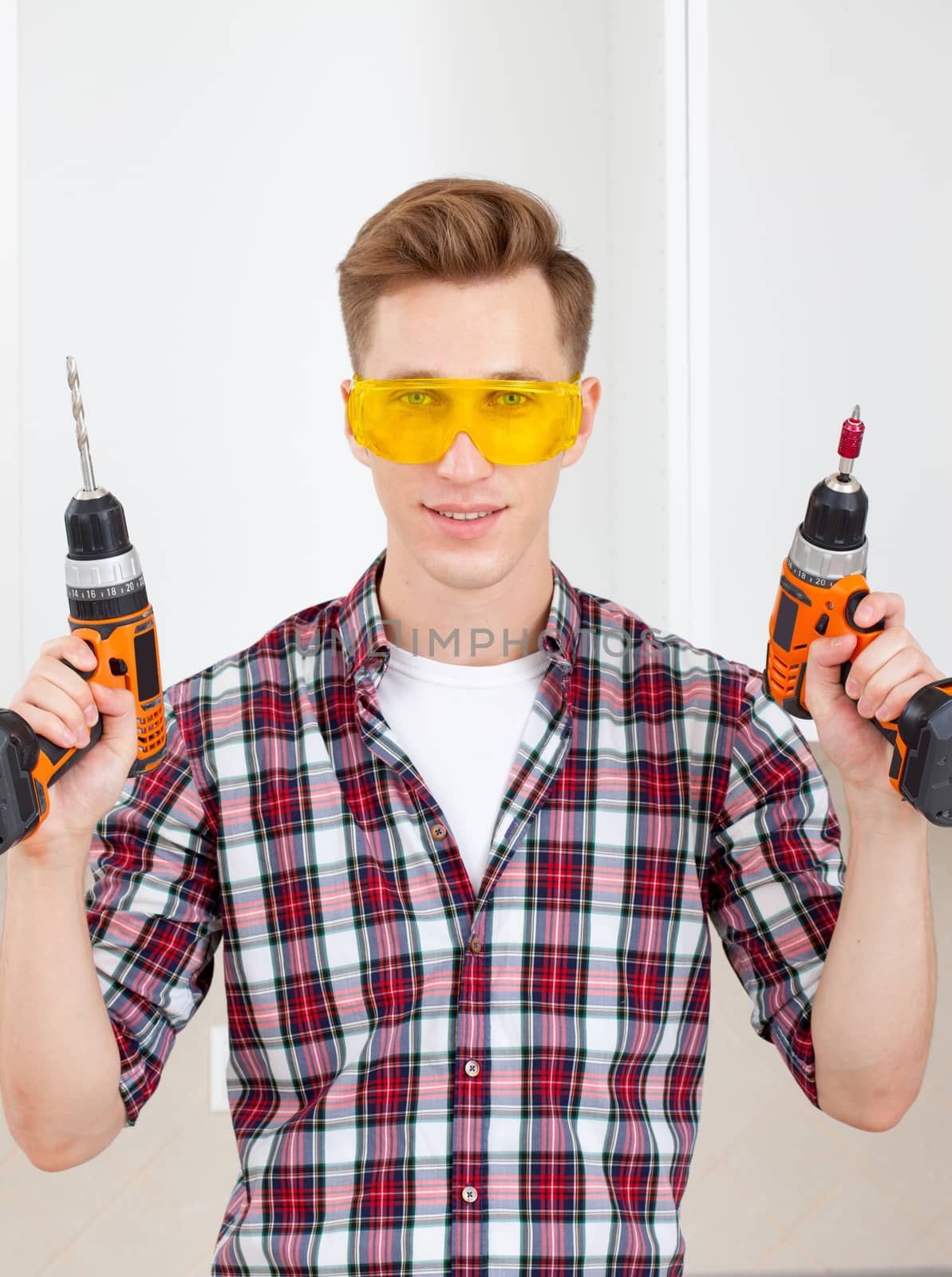 professional repairman with a drill and a screwdriver in his hand