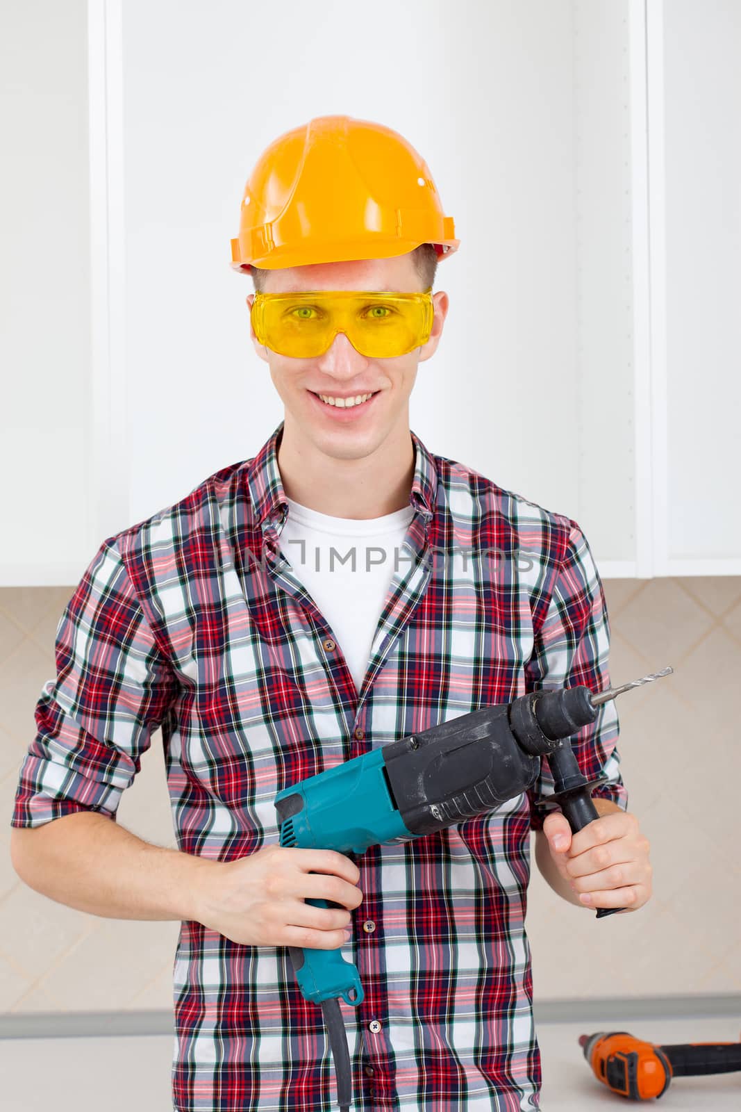 smiling worker in protective eyeglasses and orange helmet with rock-drill