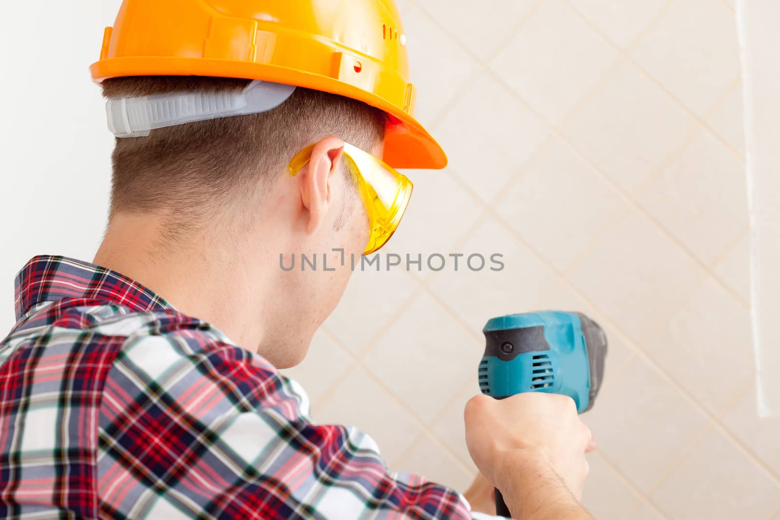 worker in protective gloves and eyeglasses with rock-drill