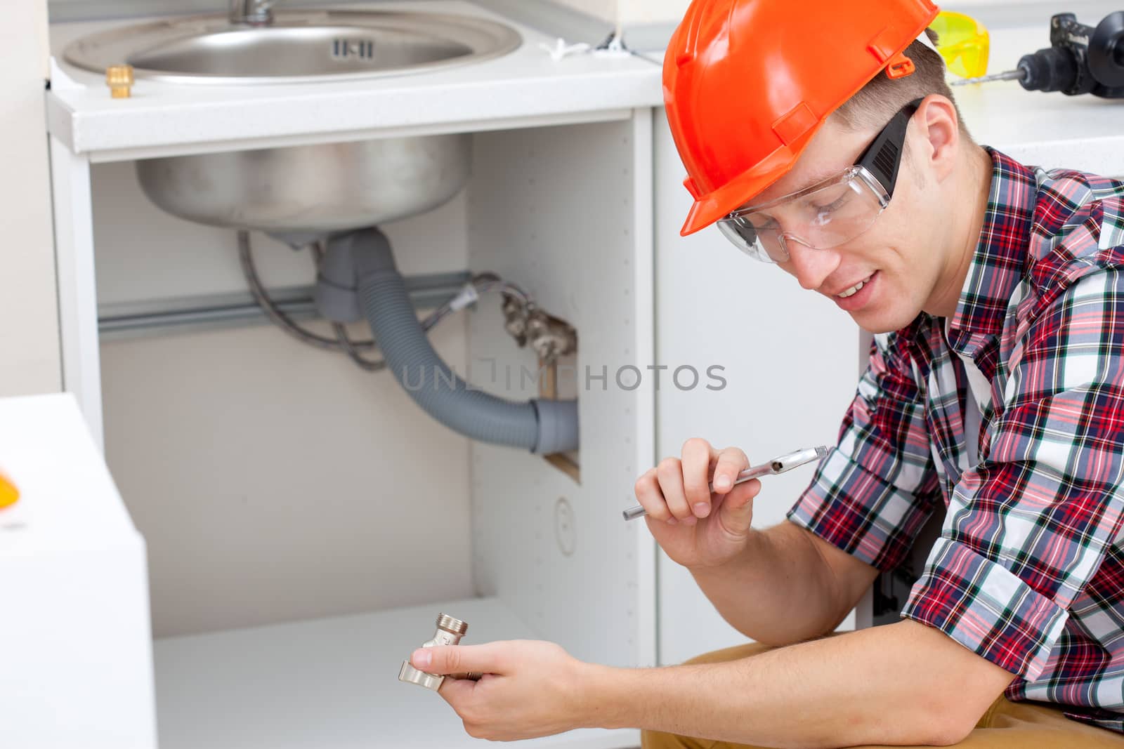 smiling mechanic adjusts the key near the kitchen sink
