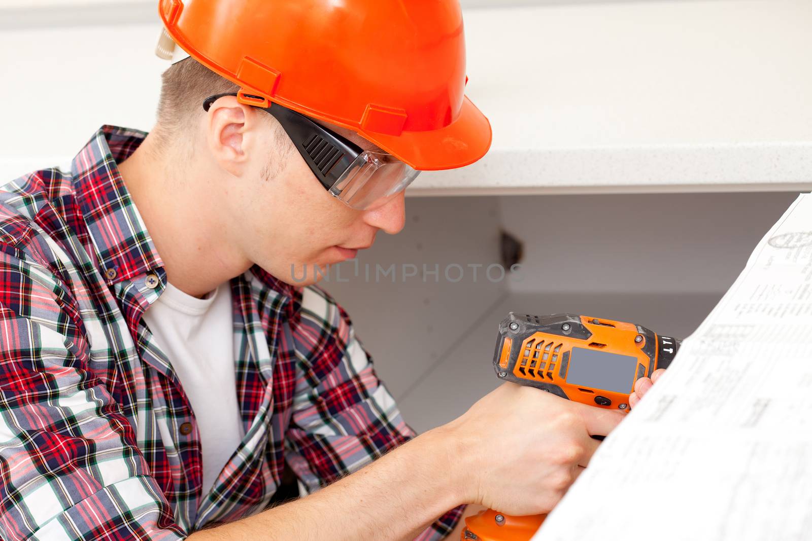 repairman at doors installation with electric drill into interior kitchen furniture