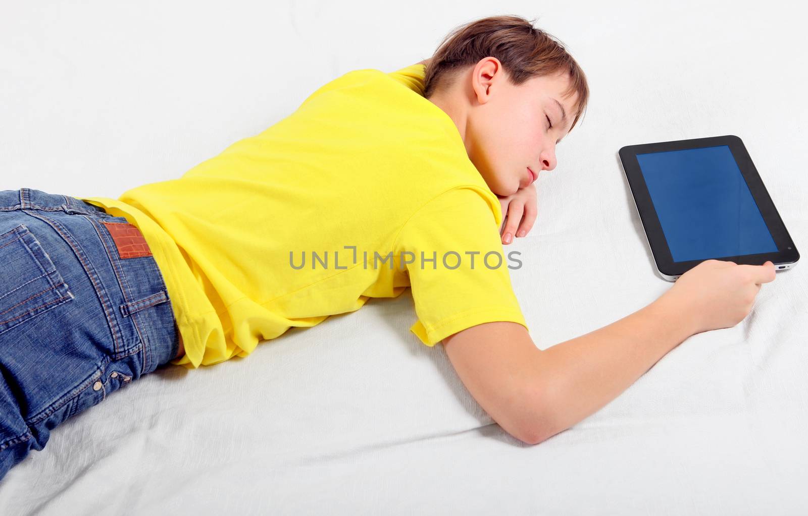 Tired Kid sleep with Tablet Computer on the Bed