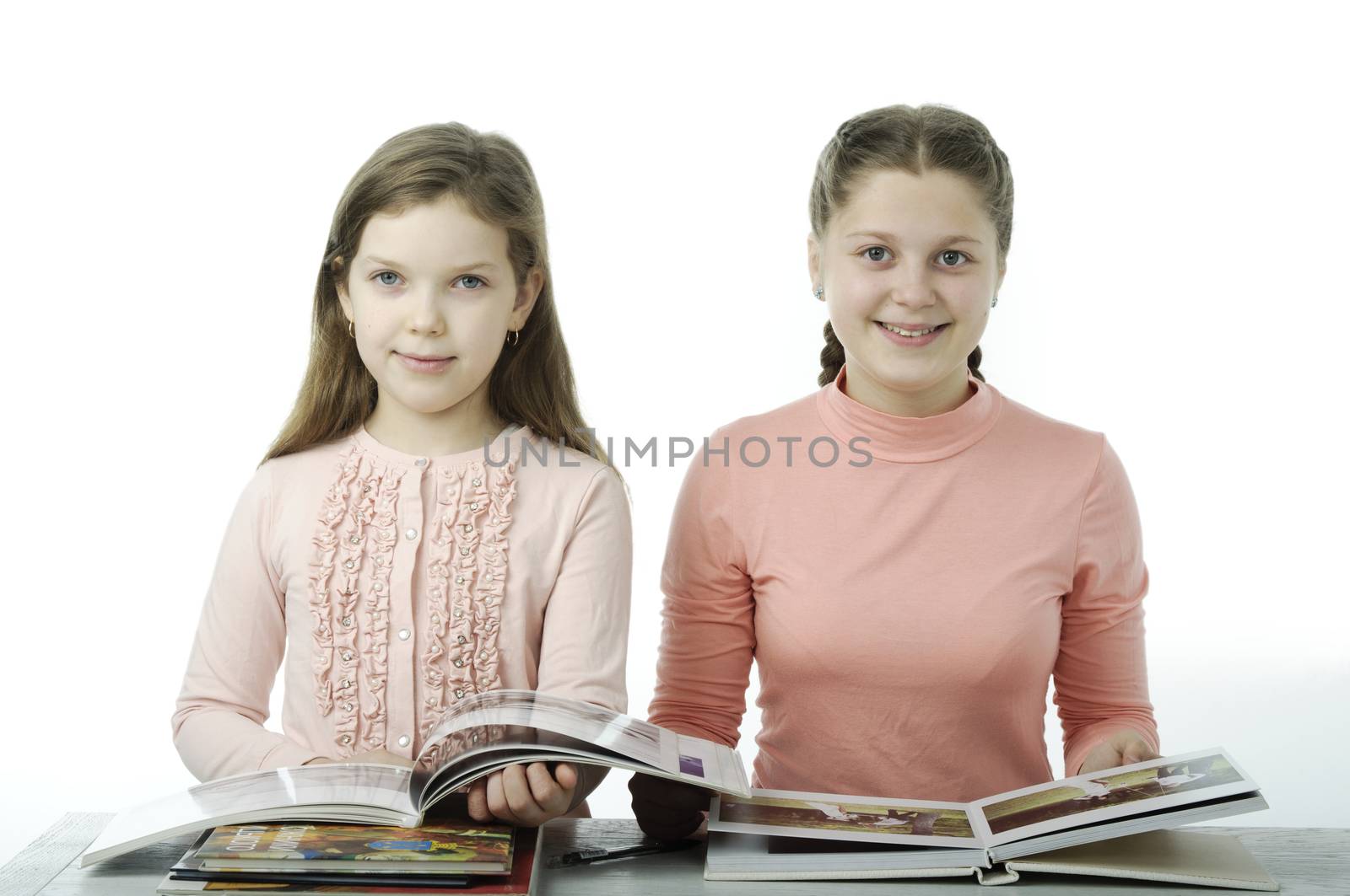 Little girls read books at the table on white by velkol