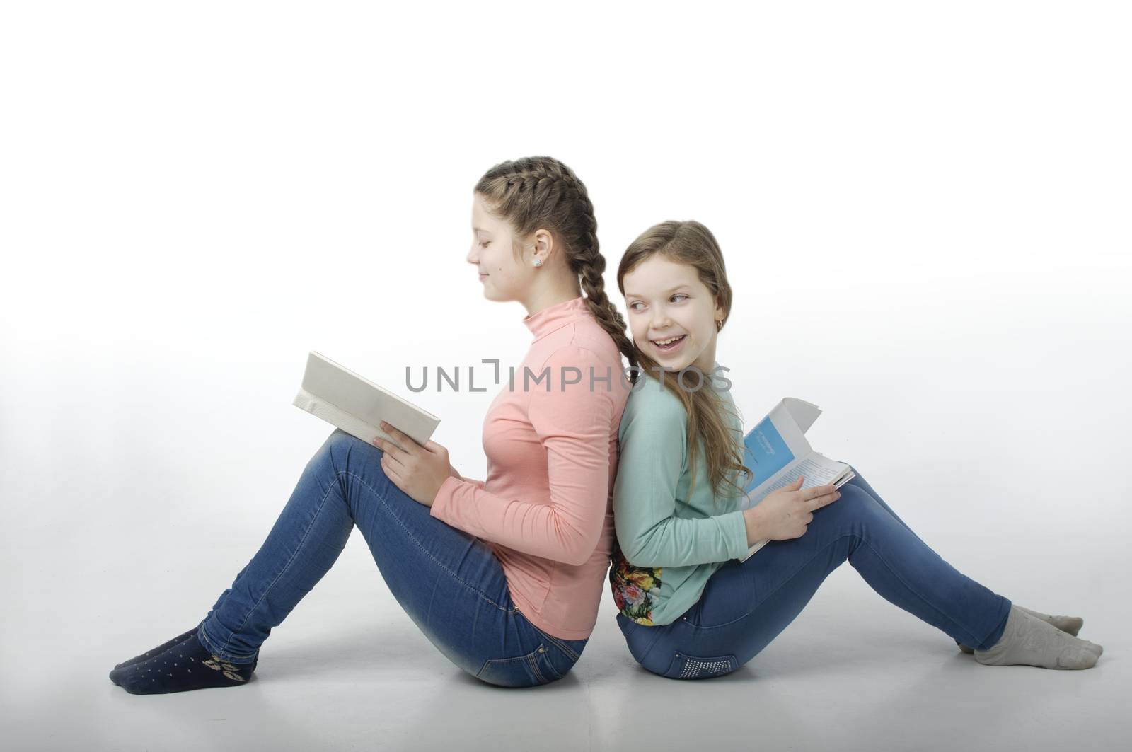 Little girls read books back to back isolated on white
