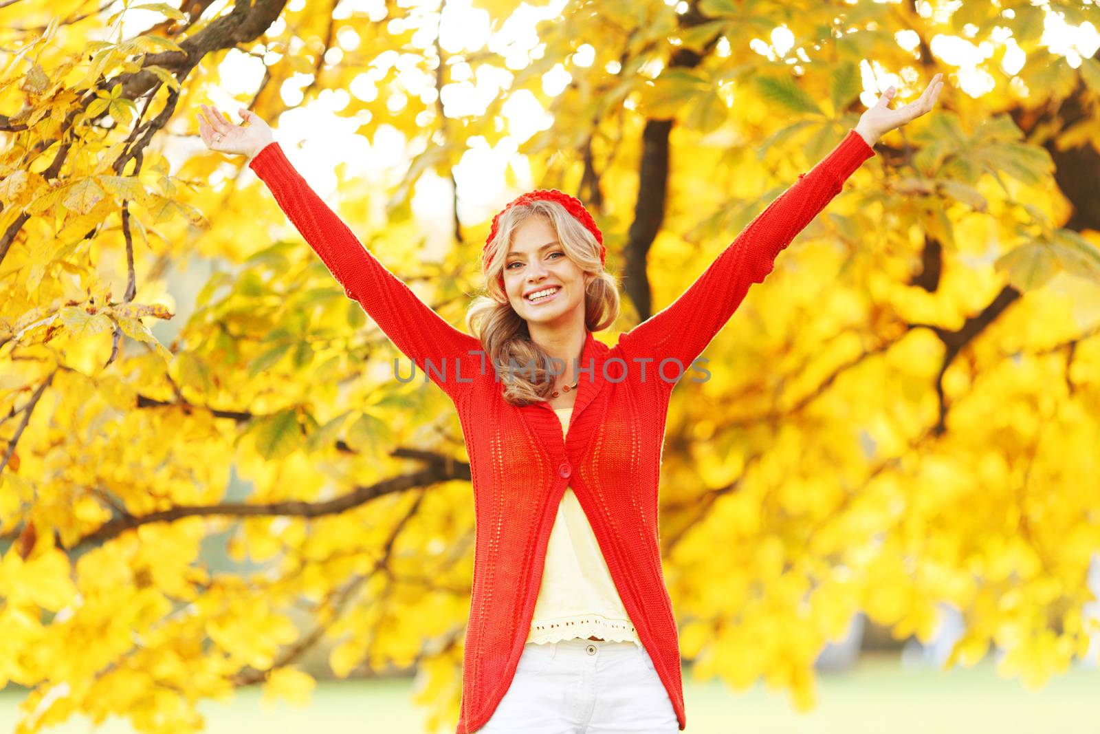 Young happy woman with raised hands in autumn park