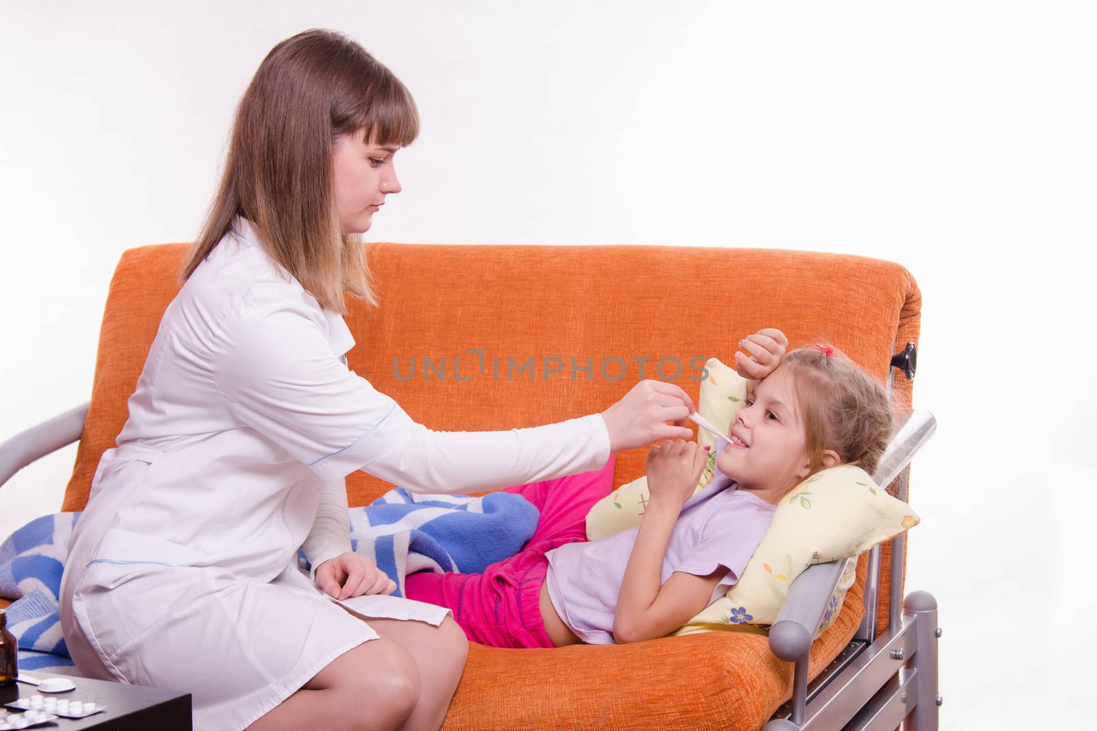 Doctor pediatrician examines a sick child at home