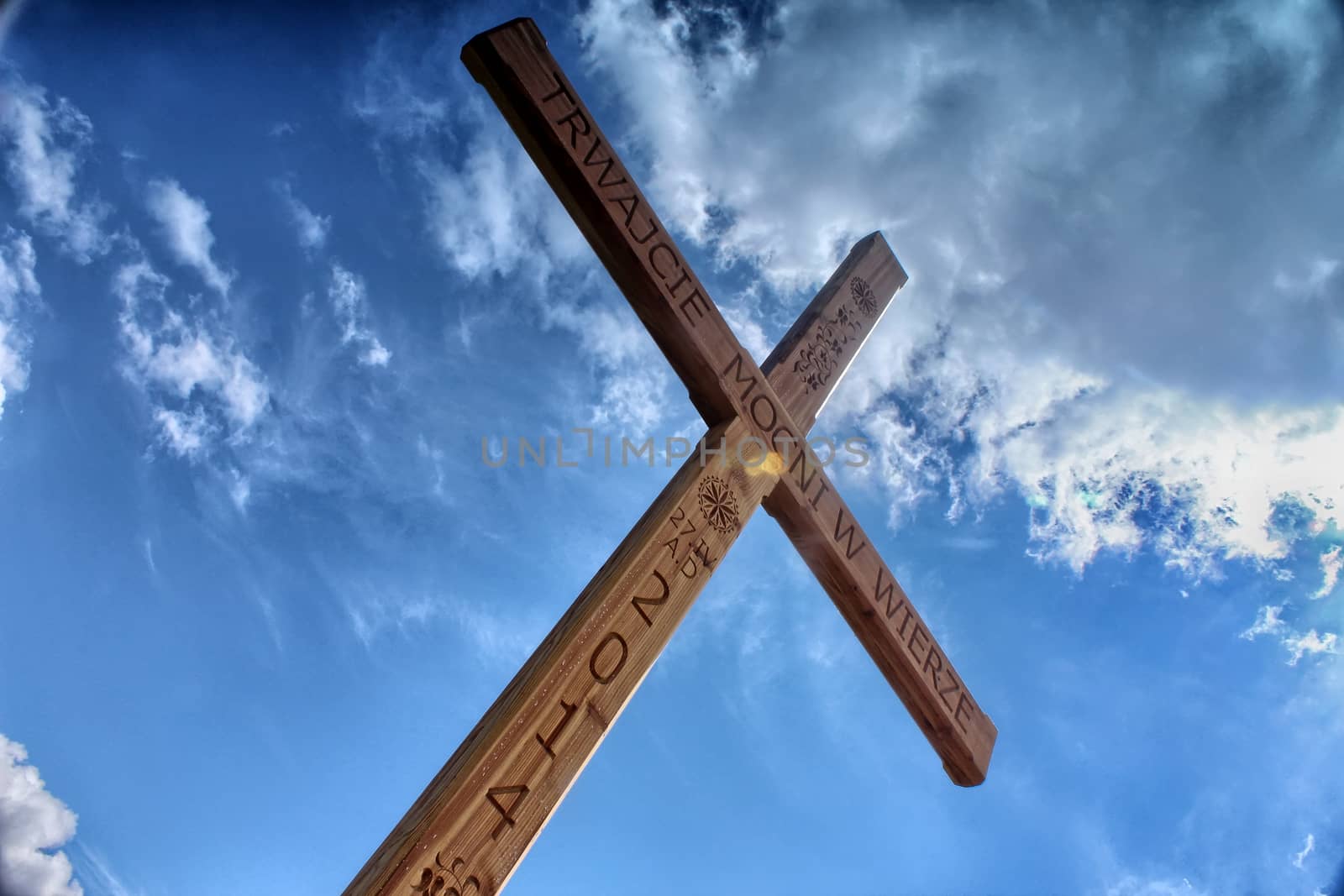 Wooden cross against a blue sky full of clouds by sanzios