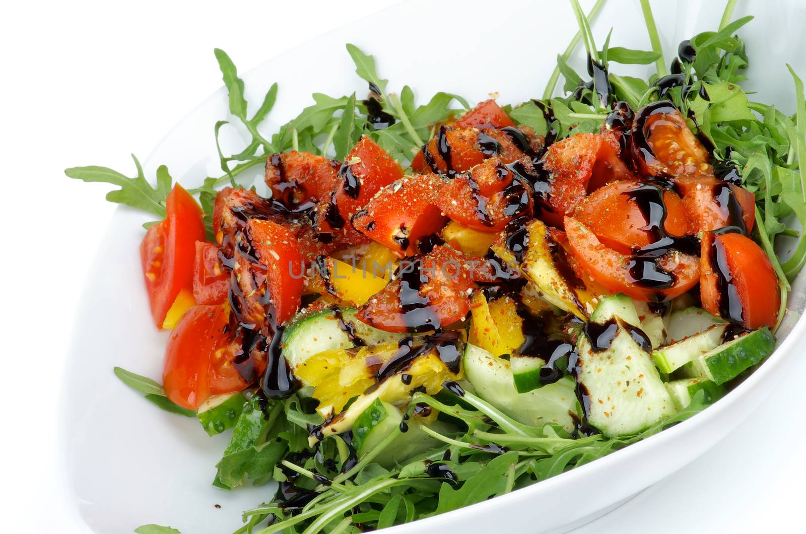 Vegetable Mix with Cucumber, Yellow Bell Pepper, Leafy Arugula, Wedges of Cherry Tomatoes, Balsamic Sauce and Spices in White Bowl closeup