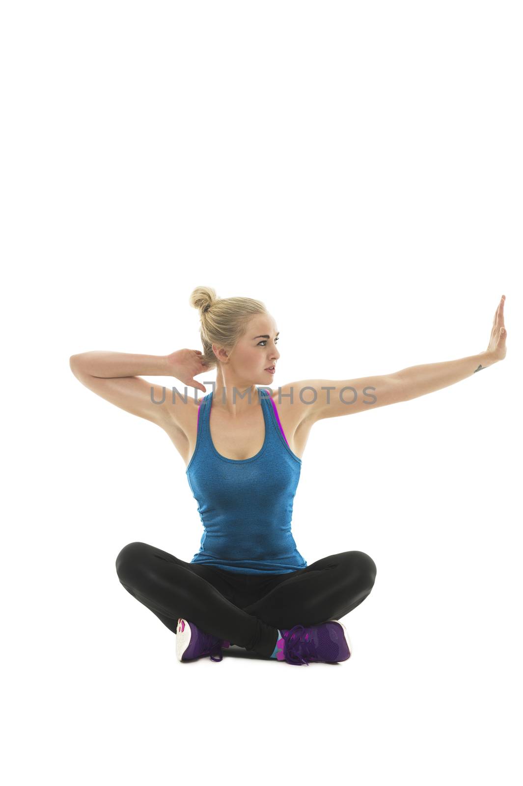 Attractive young woman working out doing yoga stretching exercises with her arms as she sits cross legged in the lotus position on the floor, over white