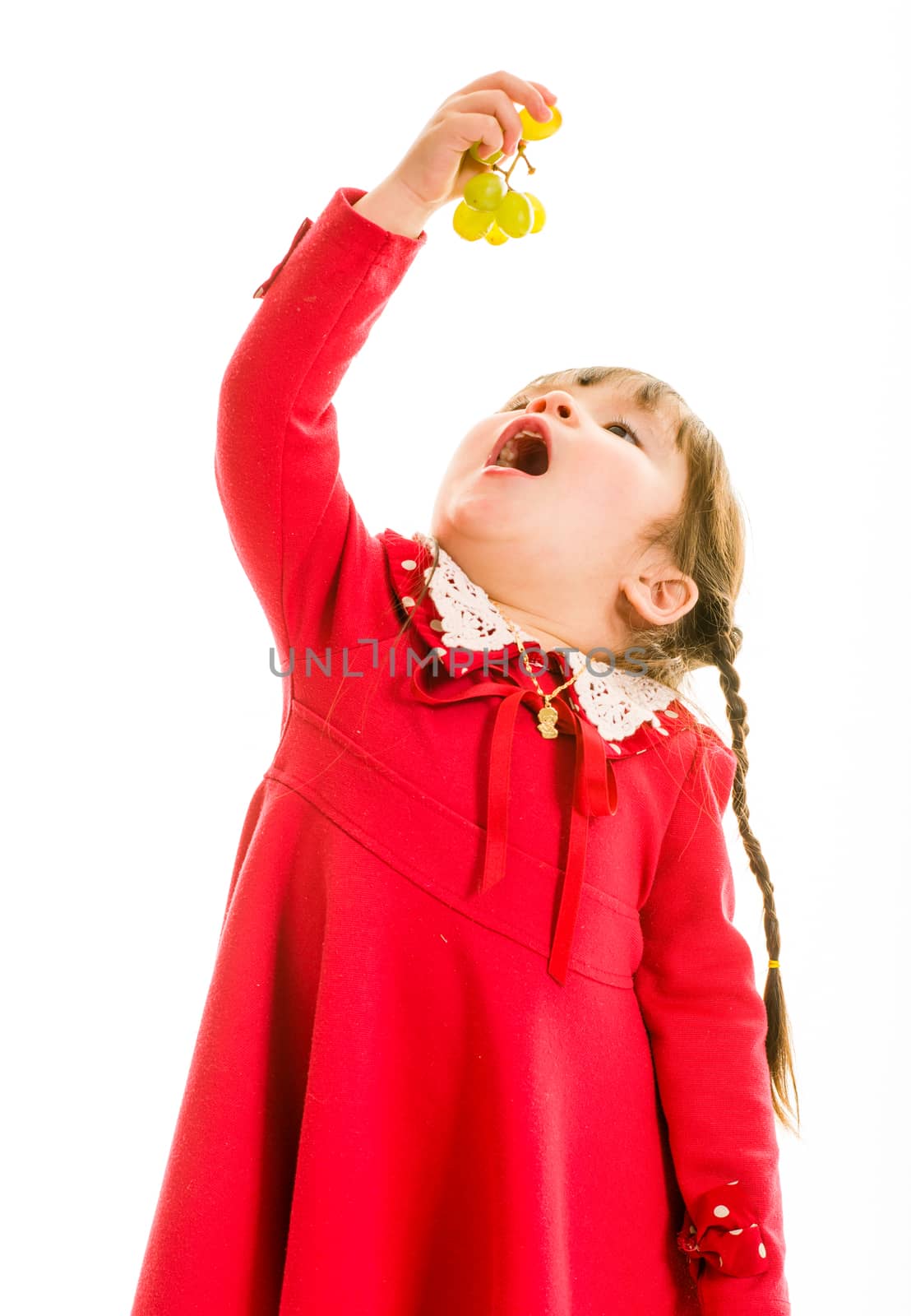Young child with green grapes in hand and open mouth
