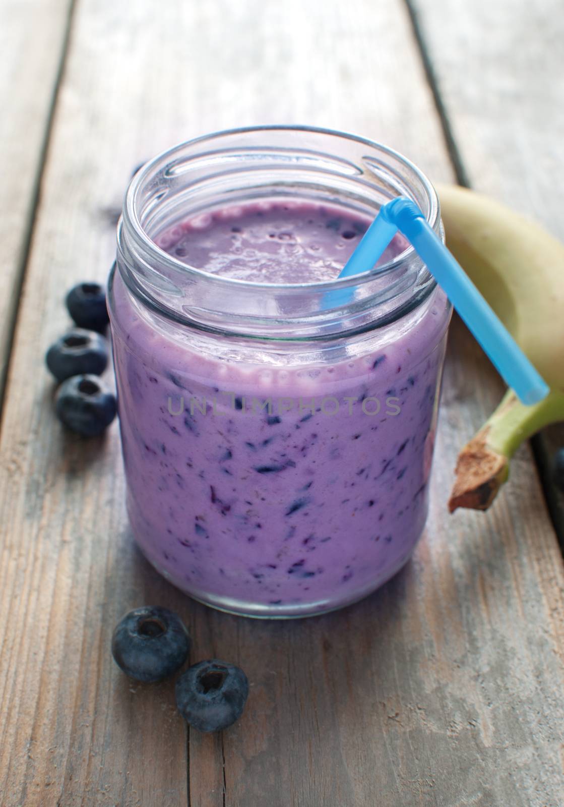 Freshly made blueberry smoothie in a jar with straw 