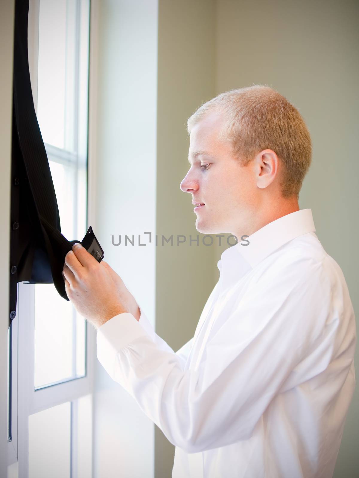 Caucasian groom checking his jacket, getting ready for his wedding