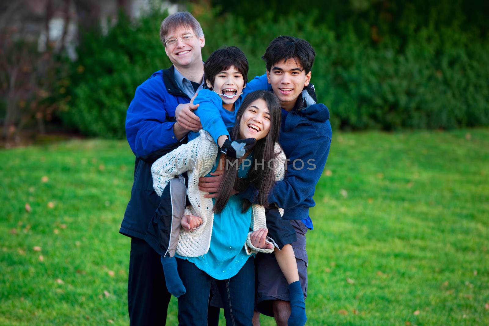 Disabled biracial child riding piggy back on his sister, family  by jarenwicklund